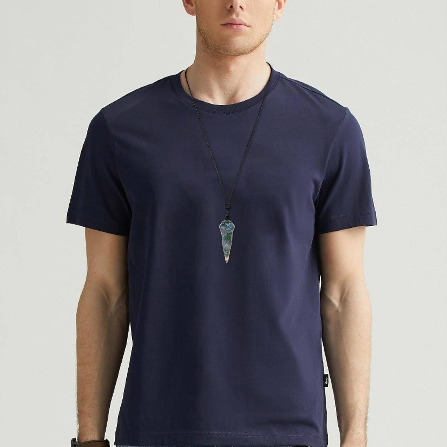 Eine Person trägt ein schlichtes marineblau-farbenes T-Shirt und eine Anhängerkette und steht vor einem hellen Hintergrund. Der Fokus liegt auf dem Shirt und dem Accessoire.