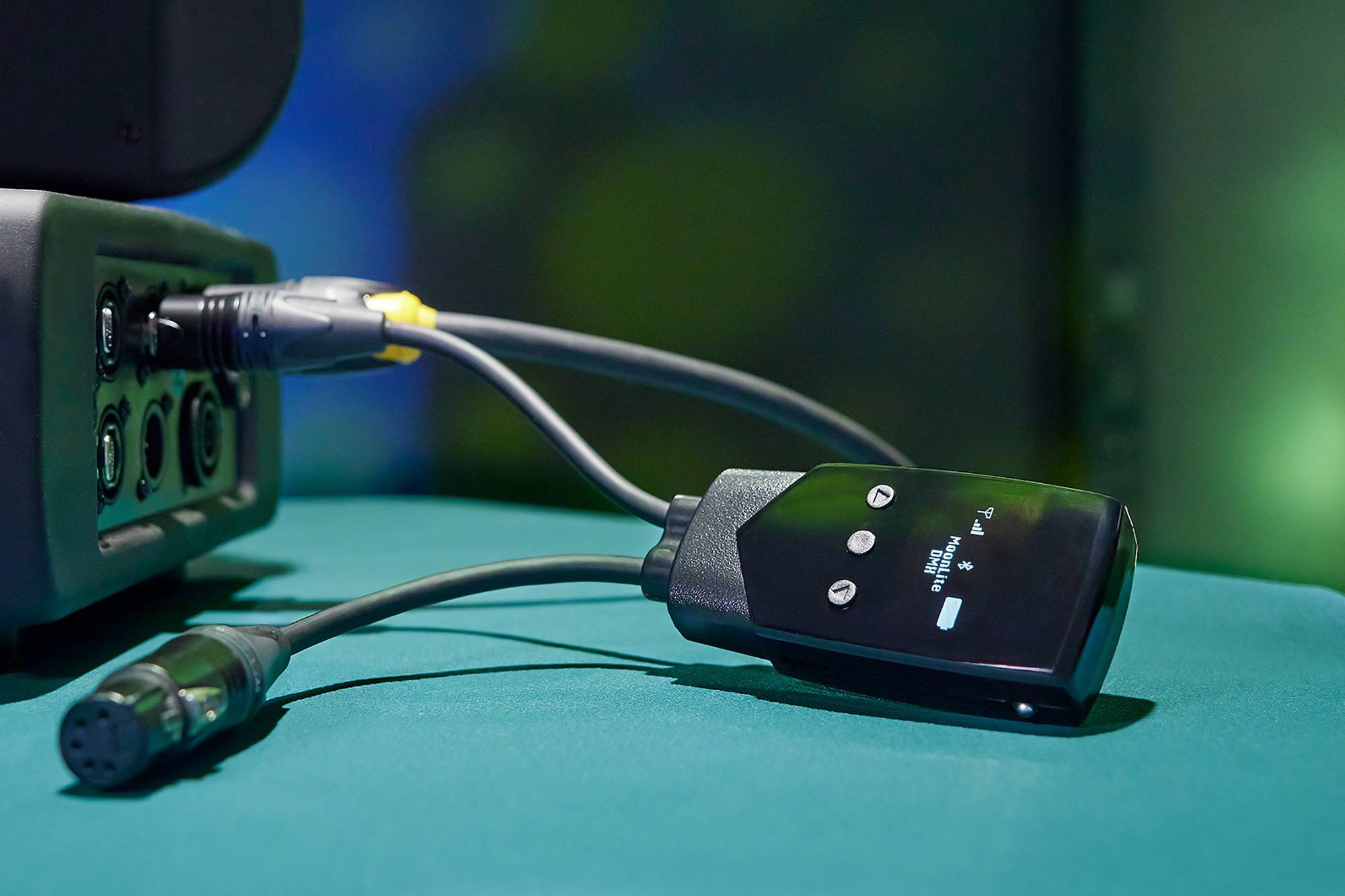 Ein schnurgebundenes Fernbedienungsgerät mit Tasten für Lautstärke und Stromversorgung liegt auf einer grünen Oberfläche.