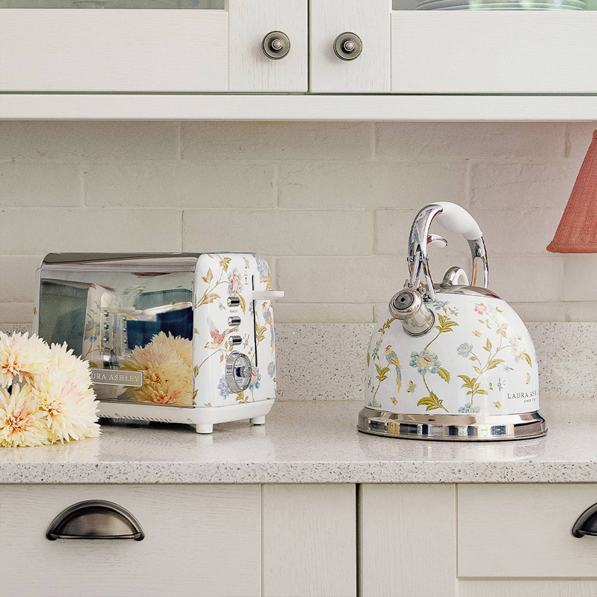 Eine Küchenarbeitsplatte mit einem Toaster und einem Elektrokessel mit Blumenmotiven. Blumentöpfe sorgen für einen dekorativen Akzent.
