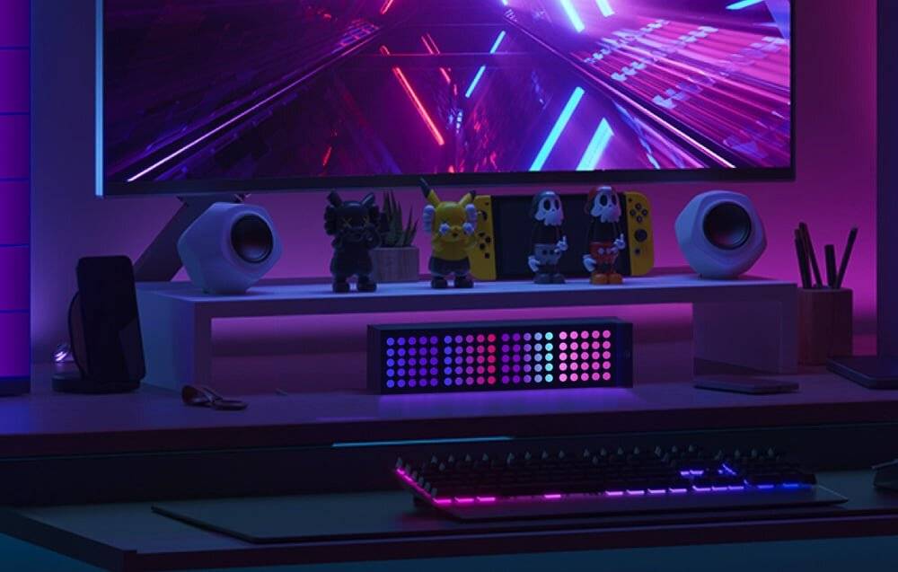 Ein Gaming-Setup mit Neonleuchten, dekorativen Figuren, einer Nintendo Switch und einer hintergrundbeleuchteten Tastatur.