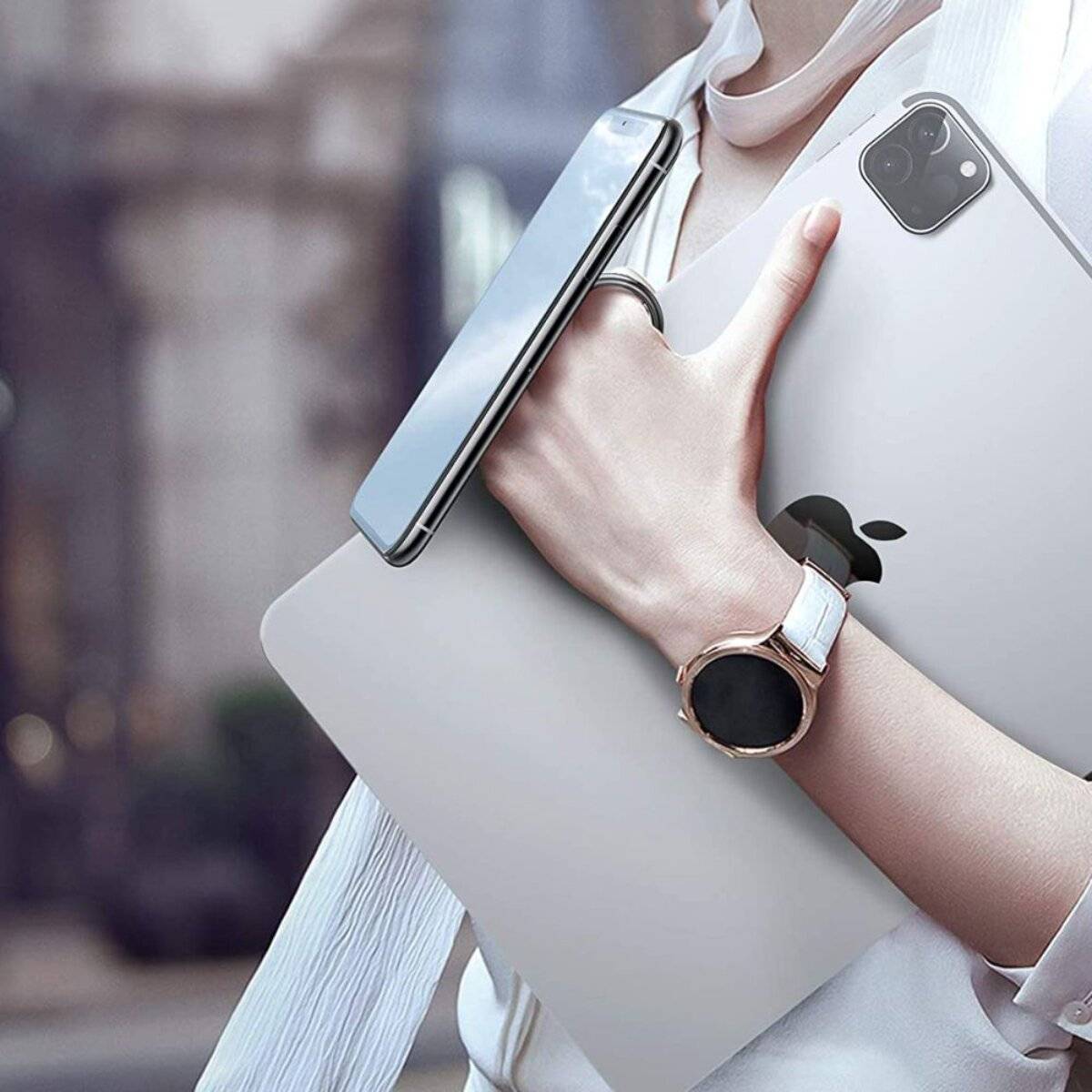 Eine Person, die einen Laptop und ein Smartphone hält, trägt eine Uhr und hat einen unscharfen Hintergrund. Der Fokus liegt auf den Geräten und Zubehör.