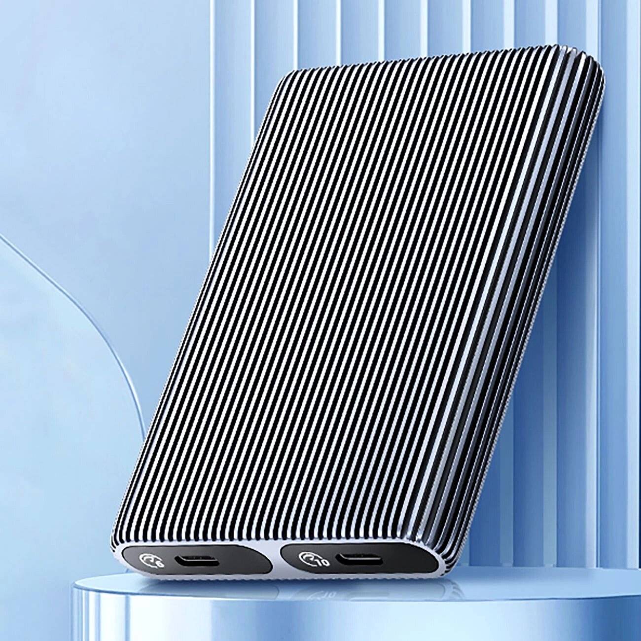 Eine elegante, moderne Powerbank mit schwarzweißem Streifendesign, die mehrere USB-Anschlüsse aufweist, steht aufrecht auf einer glänzenden Oberfläche.