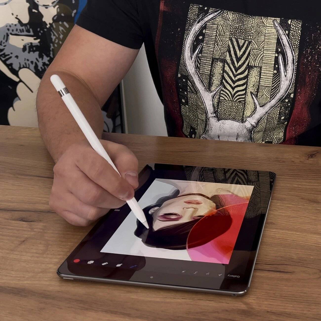 Eine Person verwendet einen Stift auf einem Tablet, um digital ein Porträt eines Frauengesichts zu zeichnen. Die Person trägt ein T-Shirt mit einem Hirschdesign.