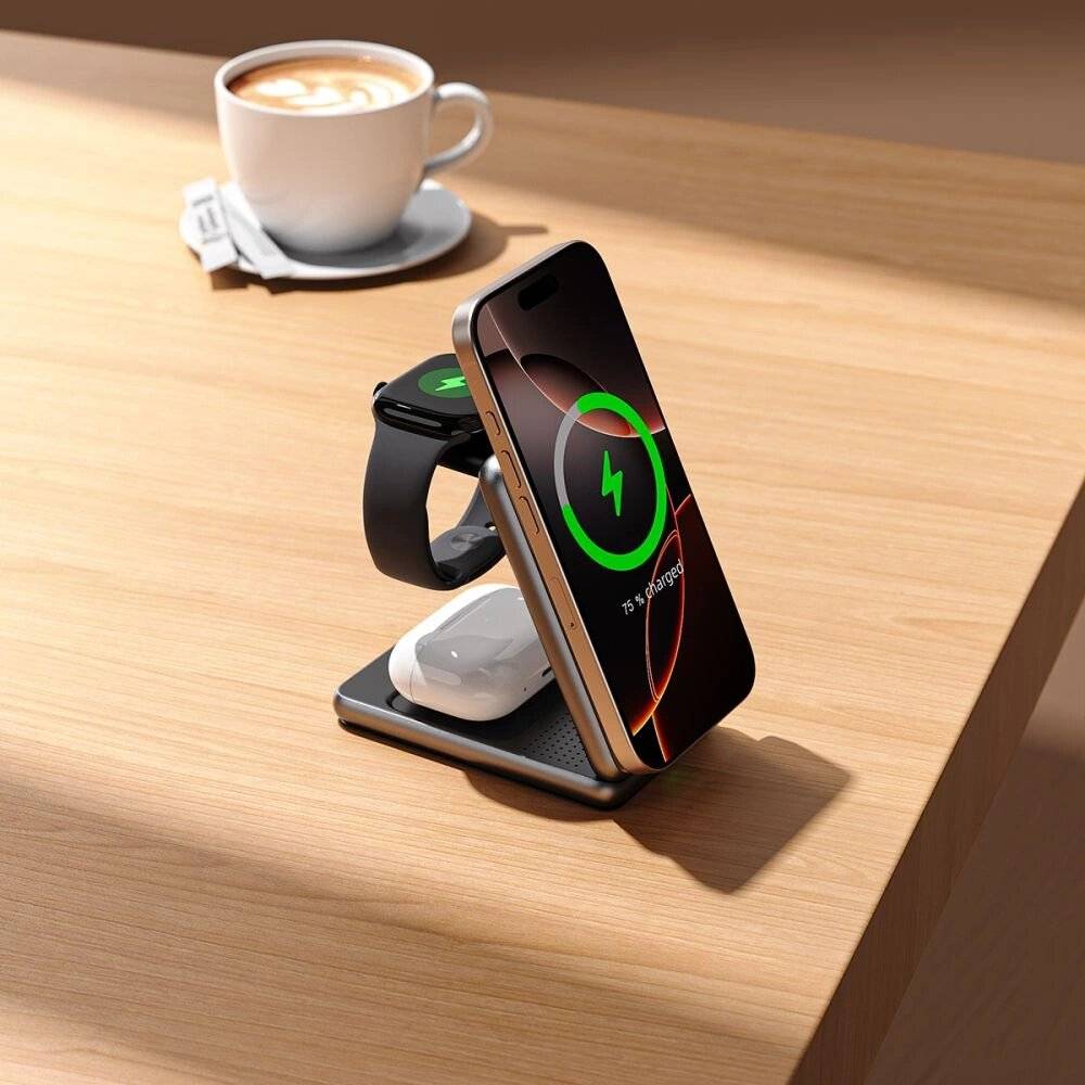 Eine kabellose Ladestation auf einem Holztisch lädt ein Smartphone, eine Smartwatch und Ohrhörer auf. Eine Tasse Cappuccino steht im Hintergrund.