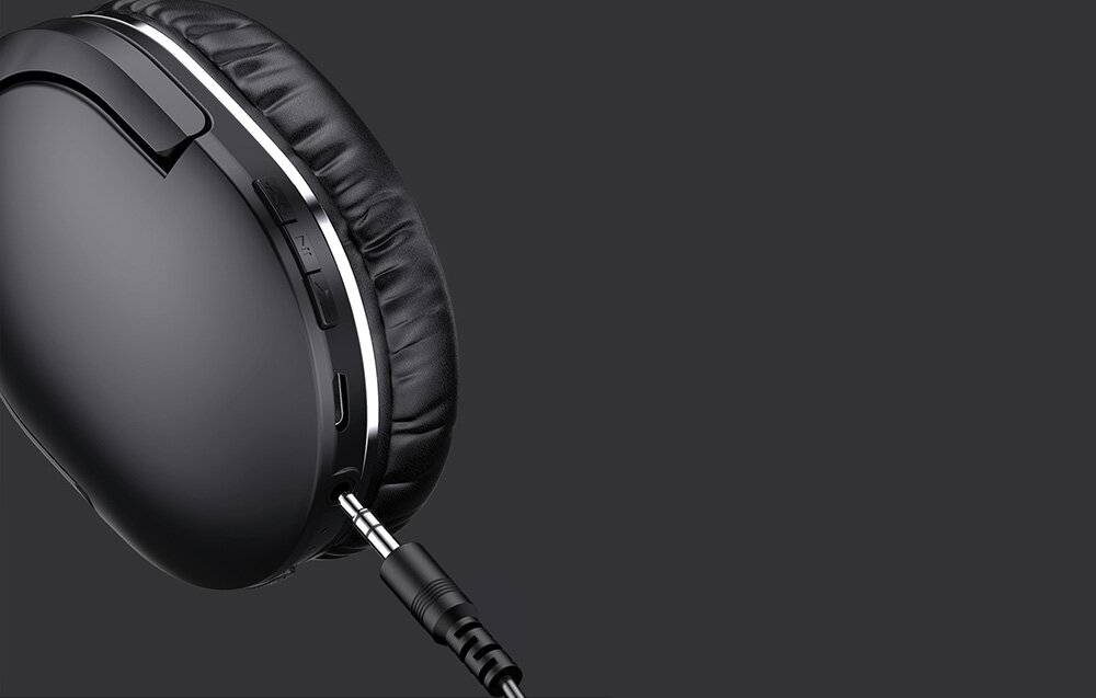 Eine Nahaufnahme von schwarzen Over-Ear-Kopfhörern mit einer sichtbaren Kopfhörerbuchse, die in den Kopfhöreranschluss eingesteckt ist und die Konnektivitätsfunktion hervorhebt.