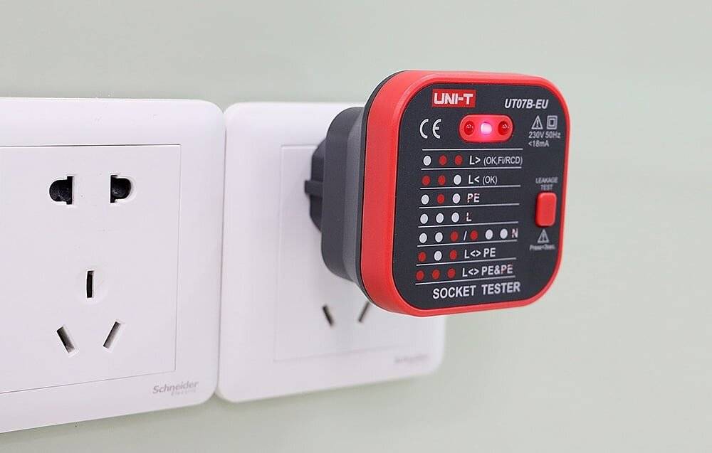 Steckdosentester in eine Wandsteckdose eingesteckt, der Anzeigelichter zur Prüfung elektrischer Steckdosenverbindungen und des Status anzeigt.