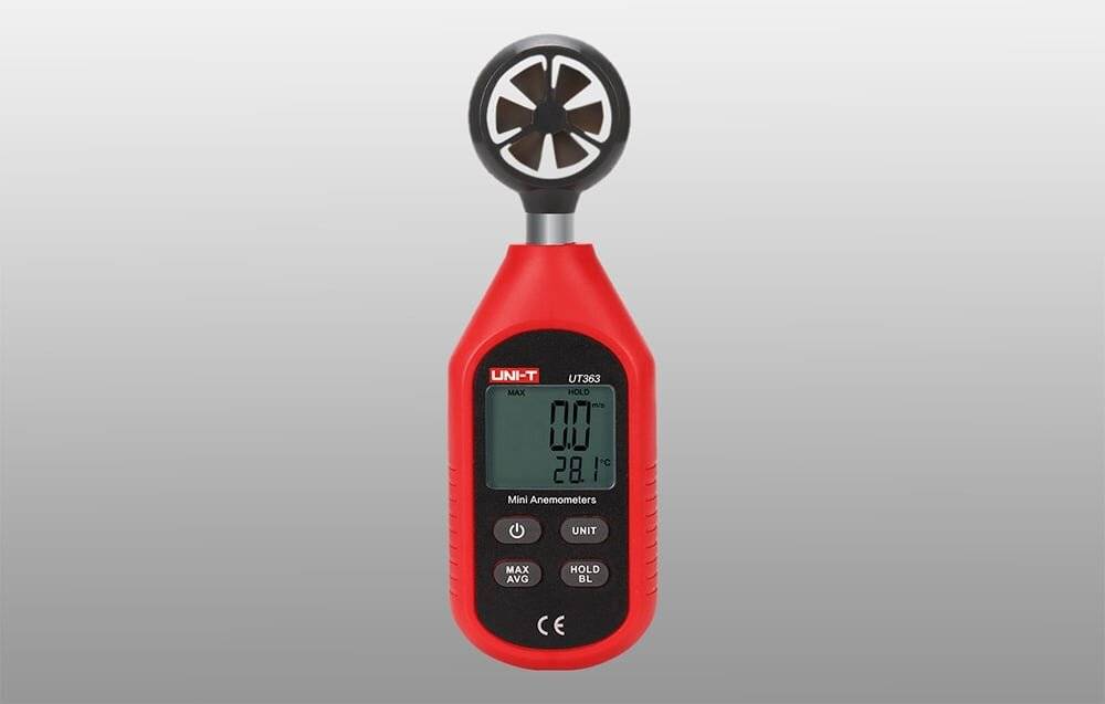 Ein digitales Anemometer mit einem Lüfter an der Spitze und einem LCD-Display, das die Luftgeschwindigkeit und Temperatur anzeigt. Rotes Kunststoffgehäuse mit mehreren Steuertasten.