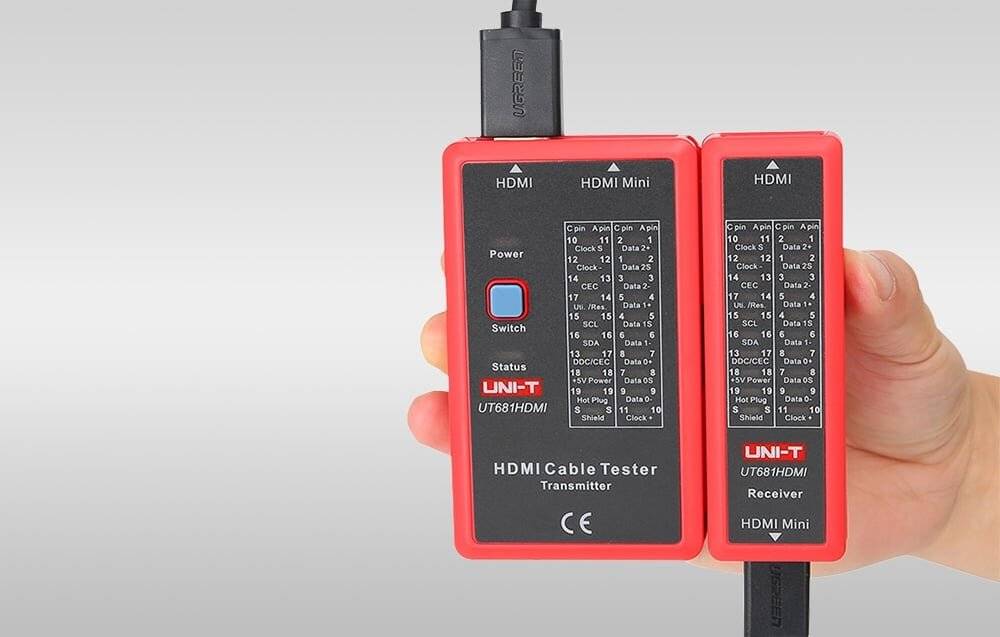 Person hält ein rotes UNI-T HDMI-Kabel-Testgerät mit zwei angeschlossenen Geräten, gekennzeichnet als Sender und Empfänger, wobei der Teststatus angezeigt wird.