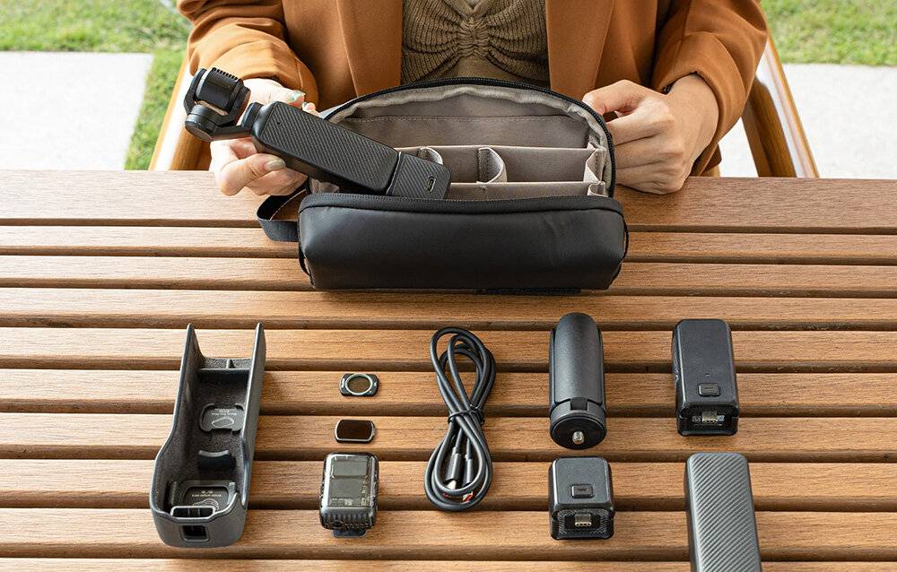 Eine Person hält einen kompakten, rechteckigen Koffer mit einem Handgelenkband, gekennzeichnet mit 