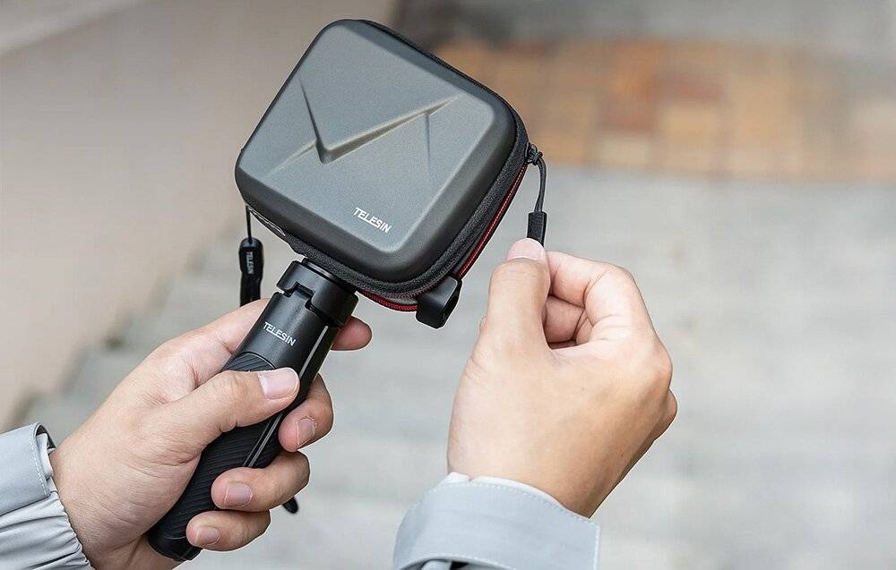 Eine Person hält ein kompaktes TELESIN-Kameragehäuse und einen Griff mit angeschlossenen Kabeln im Freien, wodurch seine Tragbarkeit und Benutzerfreundlichkeit hervorgehoben werden.