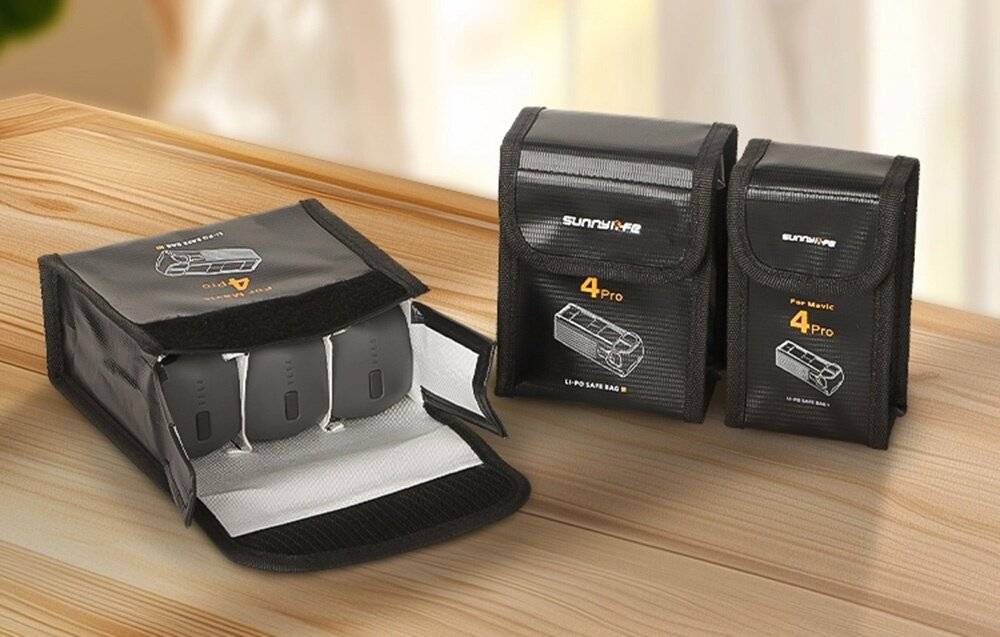 „Drei schwarze Batteriespeicherbeutel auf einer Holzoberfläche, entwickelt für Sicherheit. Zwei geschlossen und einer offen, wobei die Fächer sichtbar sind.