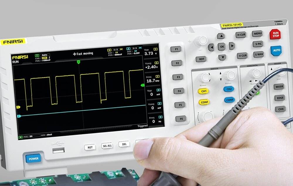 Ein Oszilloskop-Bildschirm zeigt ein Wellenformmuster mit einer Hand, die die Sonde einstellt, und zeigt technische Details wie Frequenz und Spannung.