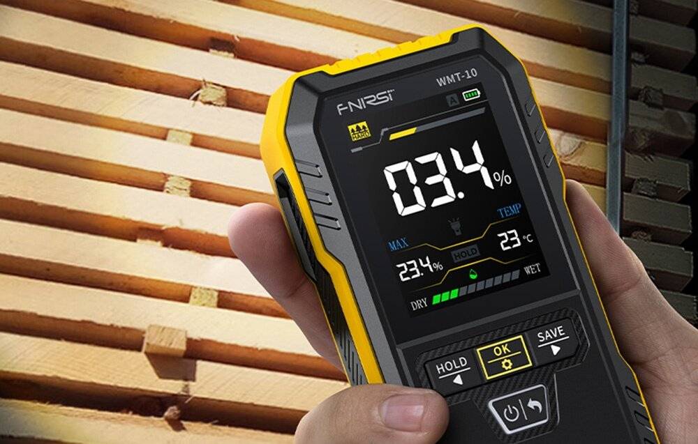 Ein tragbares digitales Gerät, das Feuchtigkeitgehalt und Temperatur misst, wird auf einem Stapel von Holzbrettern angezeigt.