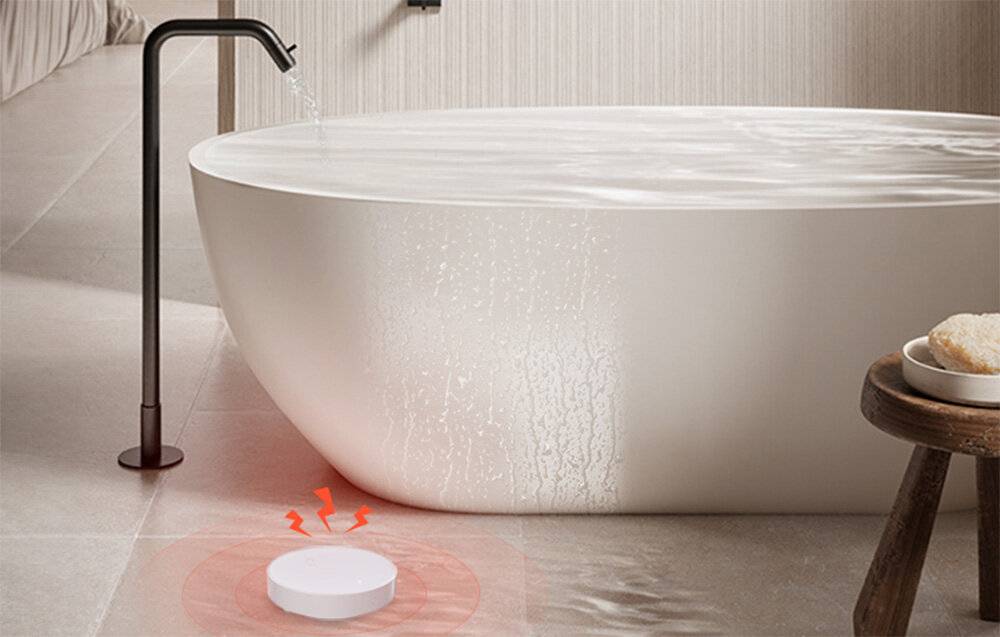 Eine runde Badewanne mit Wasser, das über den Rand überläuft, wird gezeigt. Auf dem Boden scheint ein rundes Gerät, das rote Signale aussendet, das Leck zu erkennen.