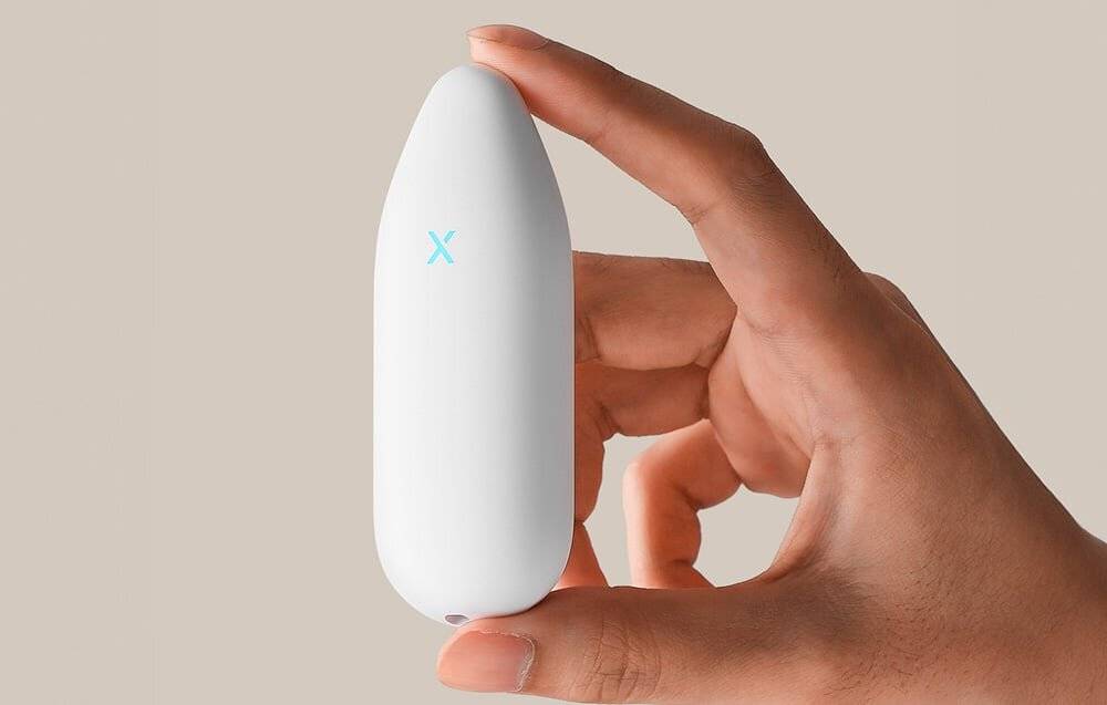 Eine Hand hält ein kleines, weißes, ovales Gerät mit einem blauen 