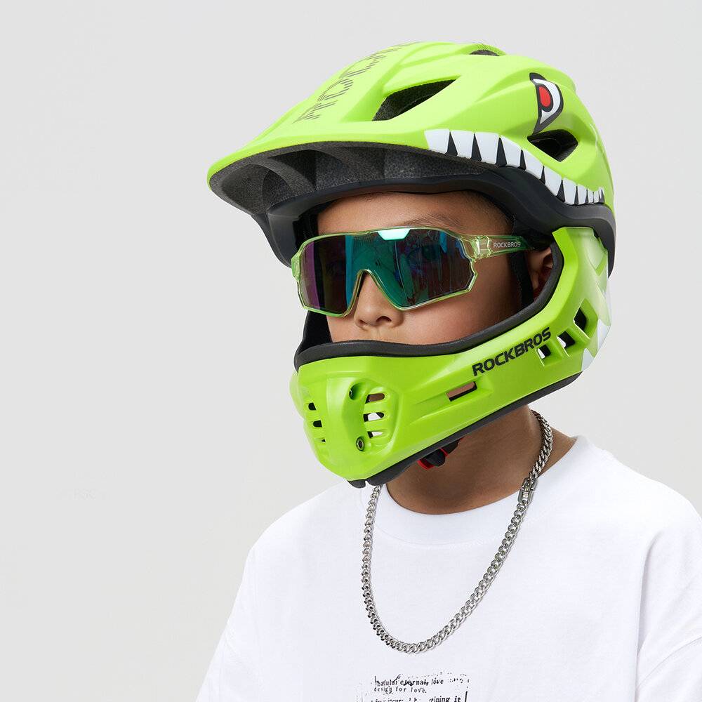 Eine Person, die einen leuchtend grünen Helm mit Zahndesign und reflektierenden Sonnenbrillen trägt und ein sportliches und schützendes Fahrradoutfit zeigt.
