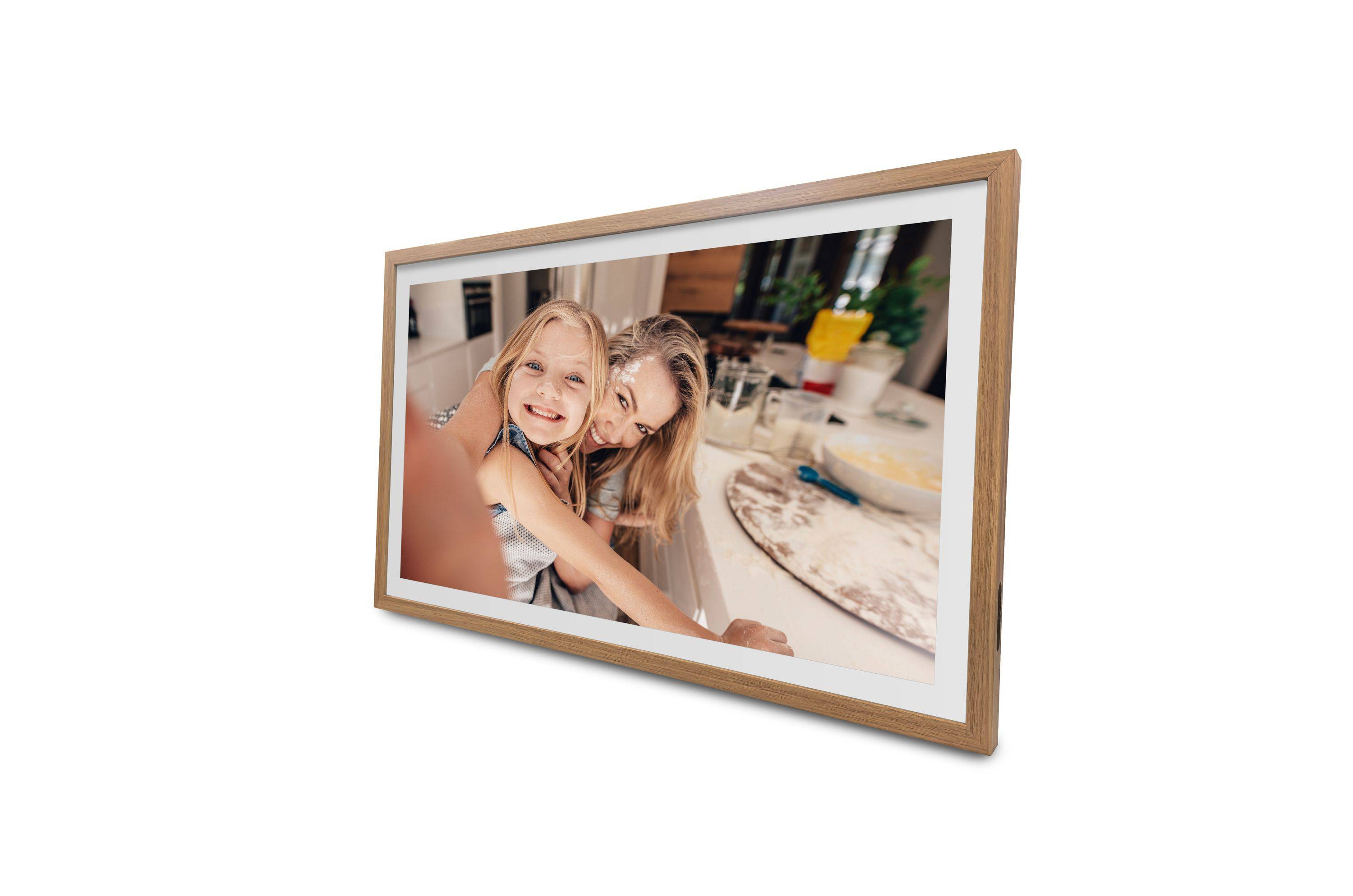 Zwei lächelnde Kinder machen ein Selfie in einer Küche, mit Zutaten und Küchenutensilien, die auf der Arbeitsfläche hinter ihnen sichtbar sind.