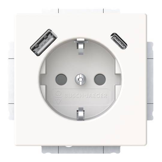 Eine weiße elektrische Wandsteckdose mit einer kreisförmigen Öffnung in der Mitte und zwei USB-Anschlüssen in den oberen linken und rechten Ecken.