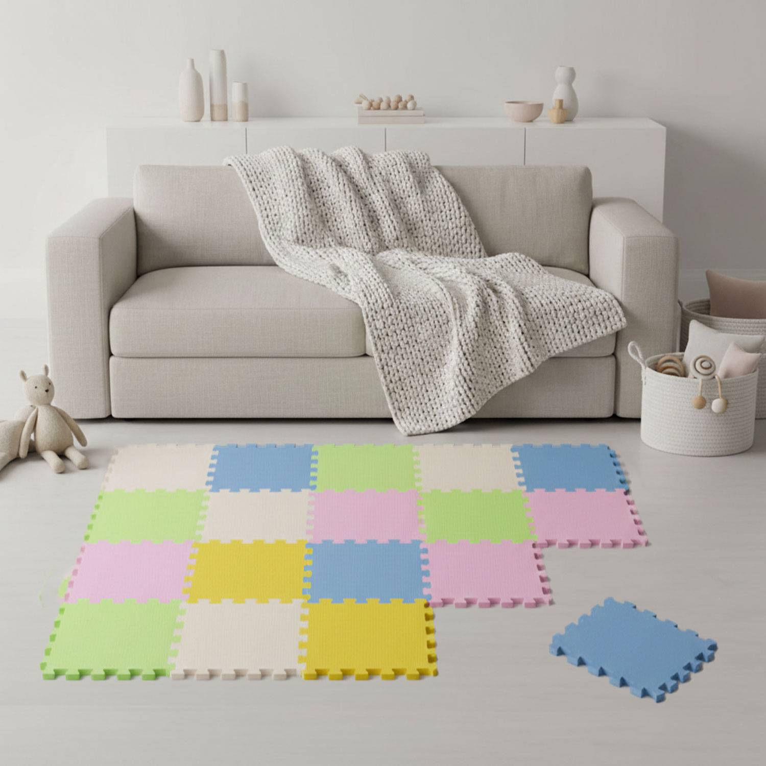 Ein gemütliches Wohnzimmer mit einem beigen Sofa, einer strukturierten Decke und einer farbenfrohen Schaumstoffmatte auf dem Boden, die einen kinderfreundlichen Spielbereich schafft.