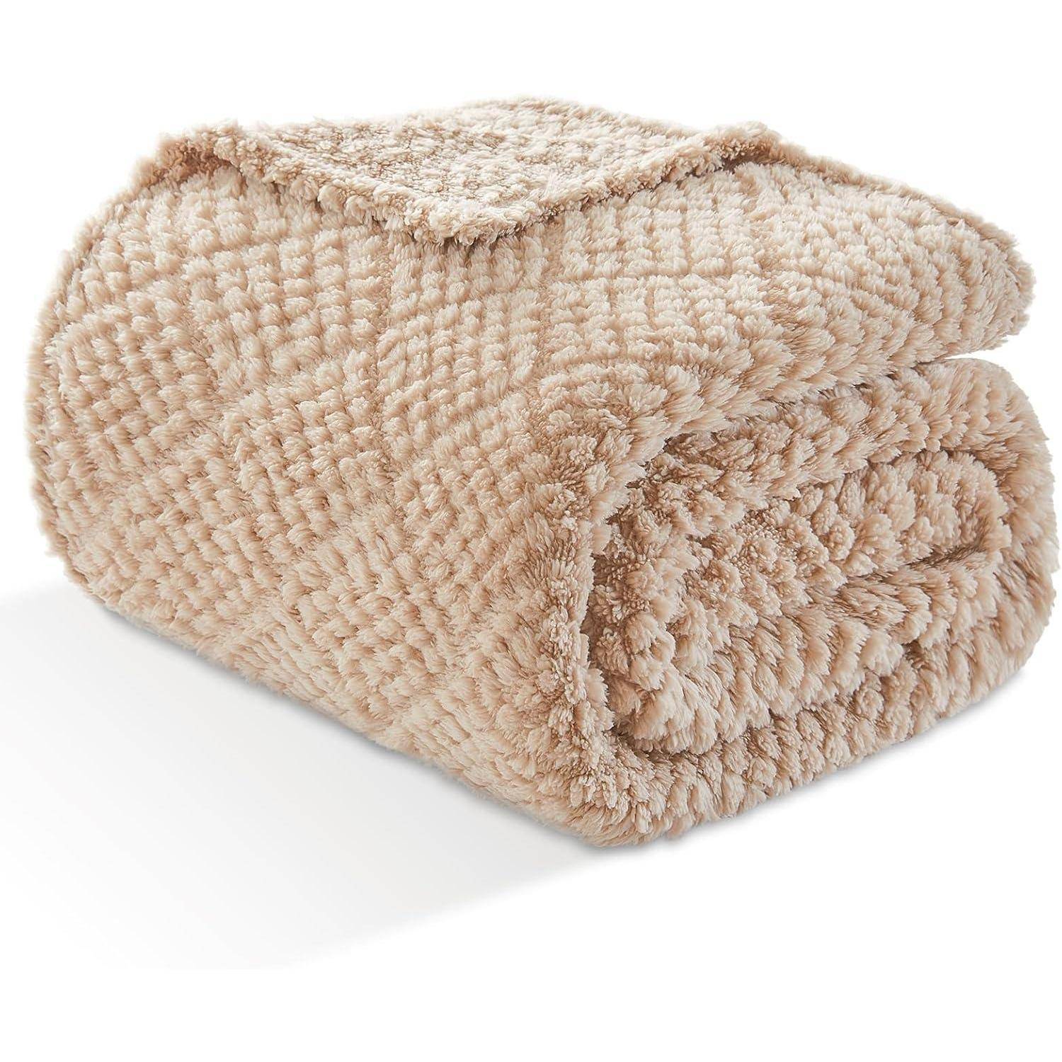 Eine flauschige, beigefarbene Strickdecke, aufgerollt und zeigt eine strukturierte, weiche Oberfläche, die sich für Wärme und Komfort eignet.
