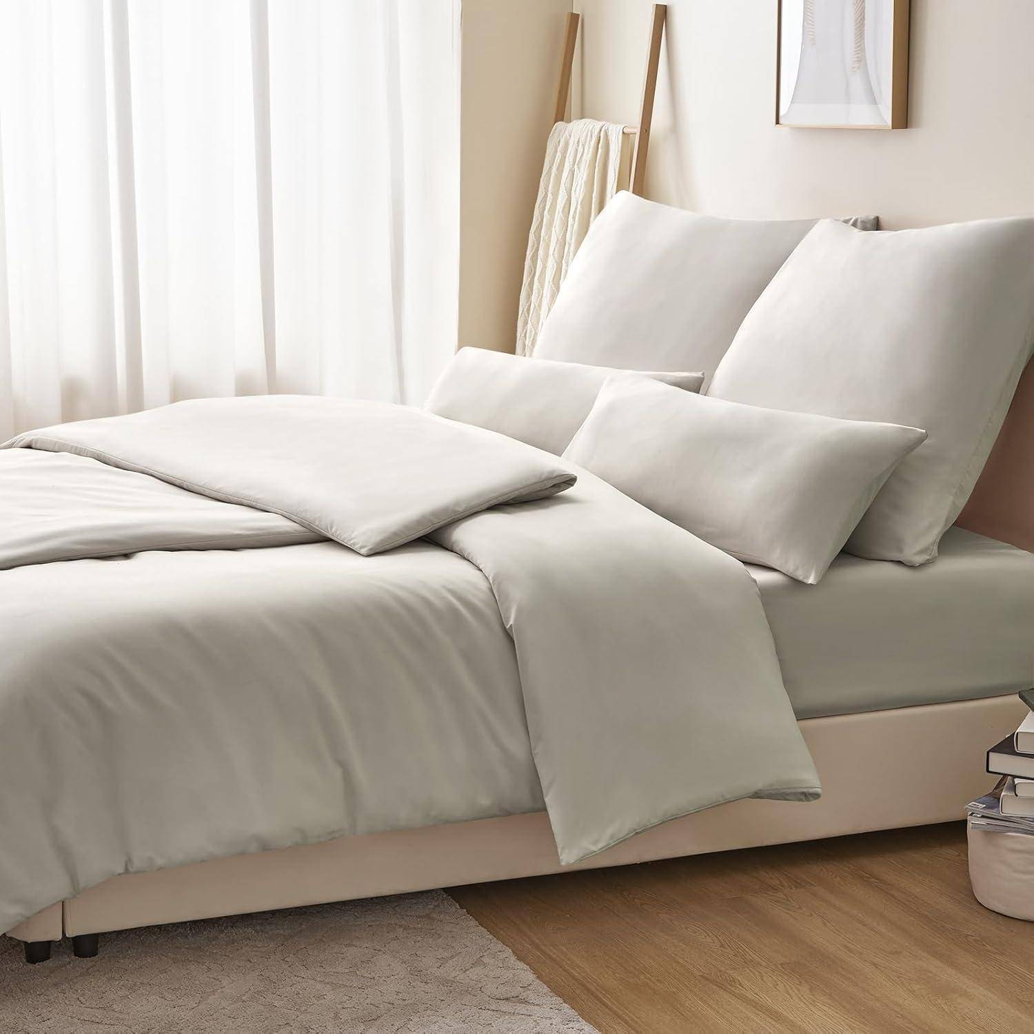 Ein ordentlich gemachtes Bett mit weißer Bettwäsche, mehreren Kissen und einer Decke in einem minimalistischen Schlafzimmer mit neutralen Farben.