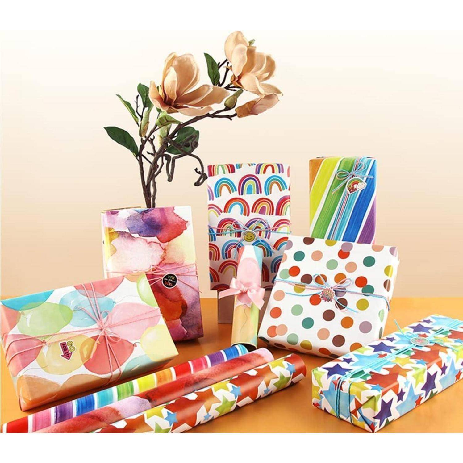 Bunte verpackte Geschenkboxen mit verschiedenen Mustern, darunter Regenbögen, Streifen und Punkte, angeordnet vor einer Blumenvase.