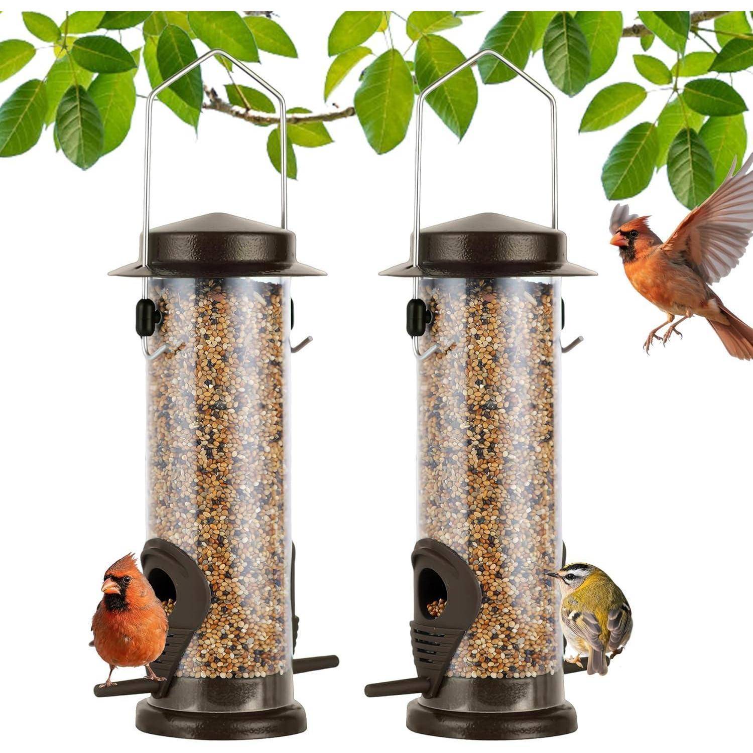 Zwei Vogelfütterungen mit Samen hängen zwischen grünen Blättern. Ein roter Vogel und ein gelber Vogel sitzen und fressen, während ein weiterer Vogel in der Nähe vorbeifliegt.