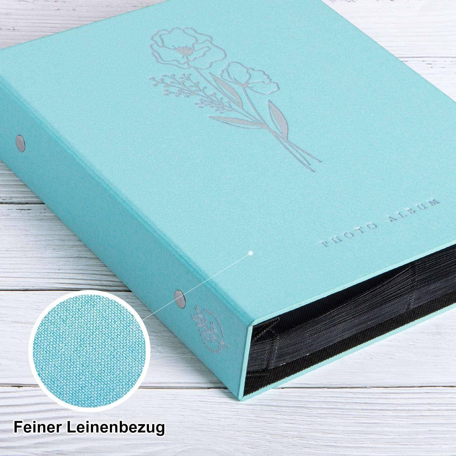 Ein hellblaues Fotoalbum mit Blumenmuster auf dem Umschlag, das auf einer weißen Holzoberfläche liegt. Eine Nahaufnahme zeigt seine Leinentextur.