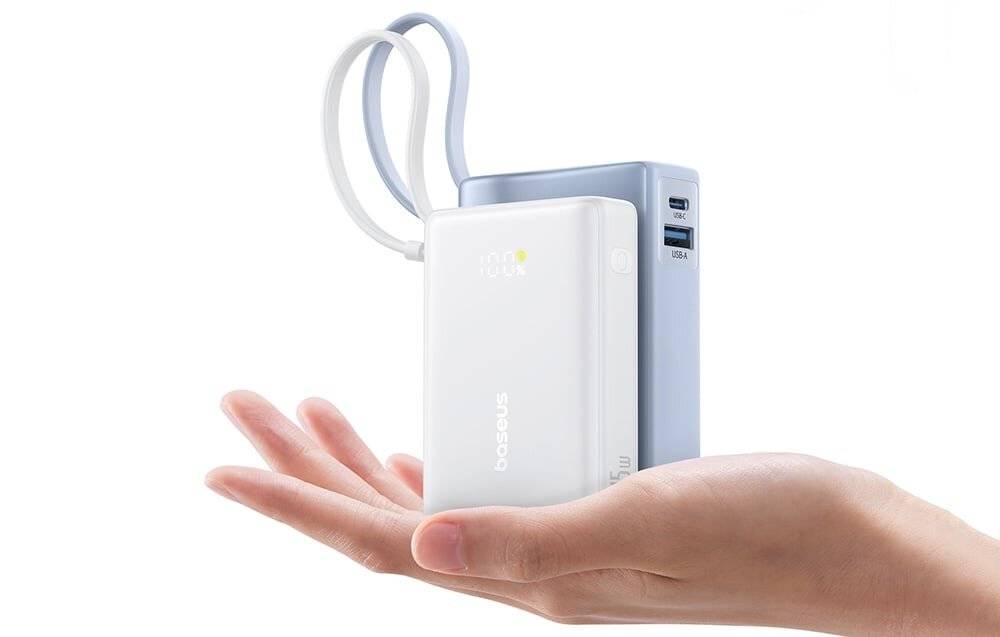 Eine Hand hält eine weiße tragbare Powerbank mit digitaler Anzeige, die 