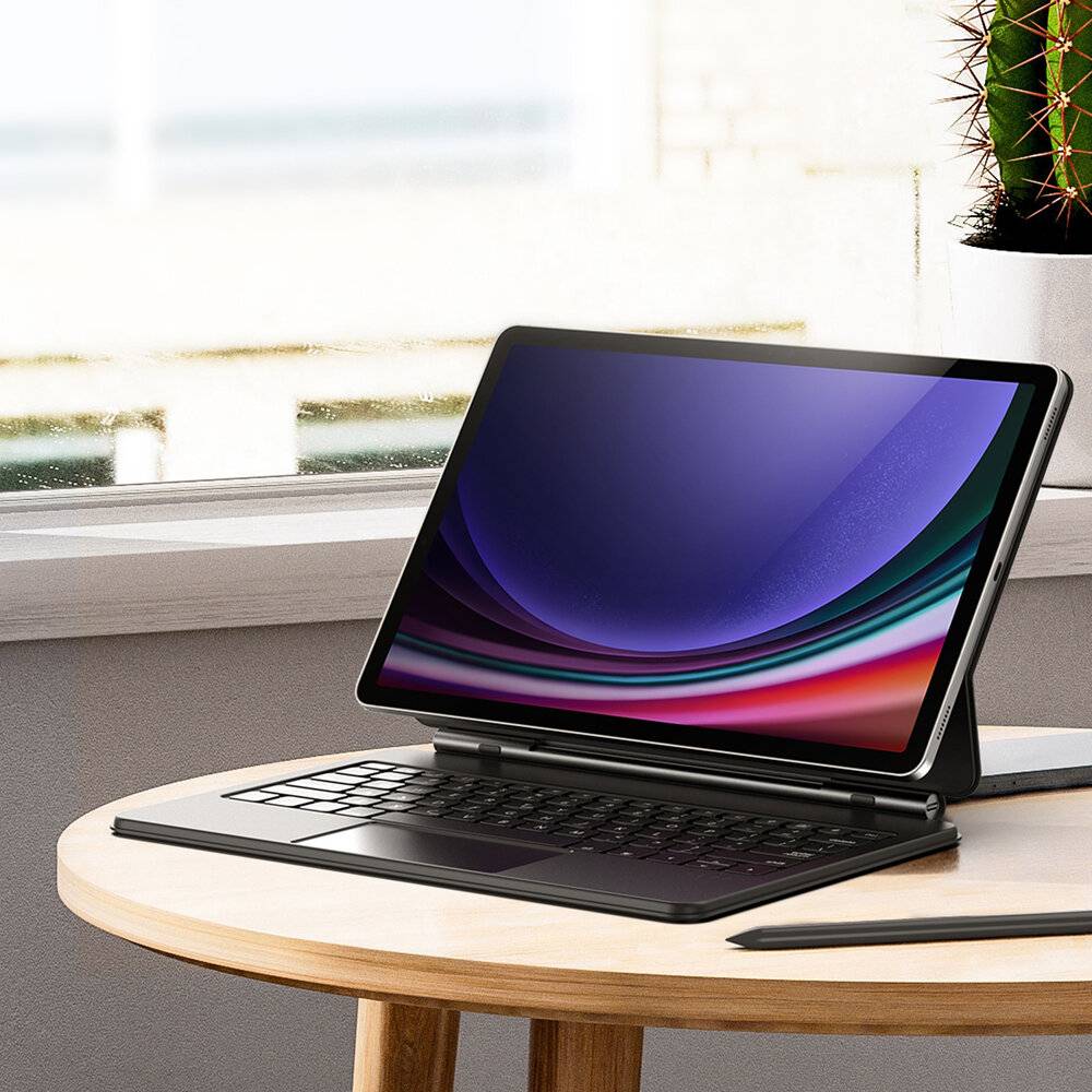 Ein schlanker, moderner Laptop mit einem farbenfrohen Bildschirm sitzt aufgeklappt auf einem runden Holztisch in einem hellen Raum, neben einem Topfkaktus.