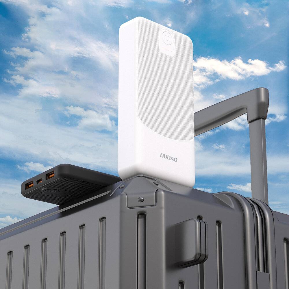 Ein weißes elektronisches Gerät auf einem Koffer vor einem blauen Himmel. Das Gerät verfügt über Anschlüsse und Tasten, was darauf hindeutet, dass es sich um ein Reisezubehör handelt.