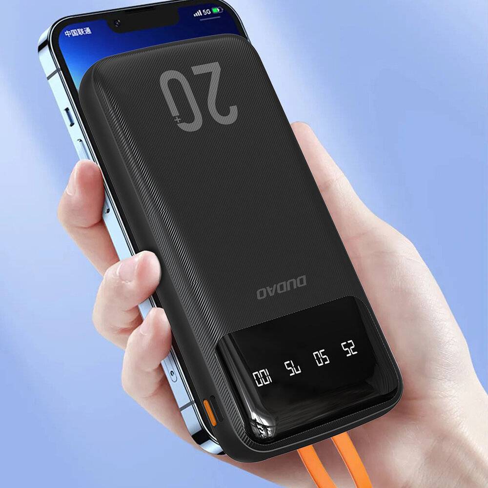 Eine Hand, die ein Smartphone mit einer angeschlossenen digitalen Powerbank hält. Die Powerbank zeigt Ladestände an und hat angeschlossene Ladekabel.