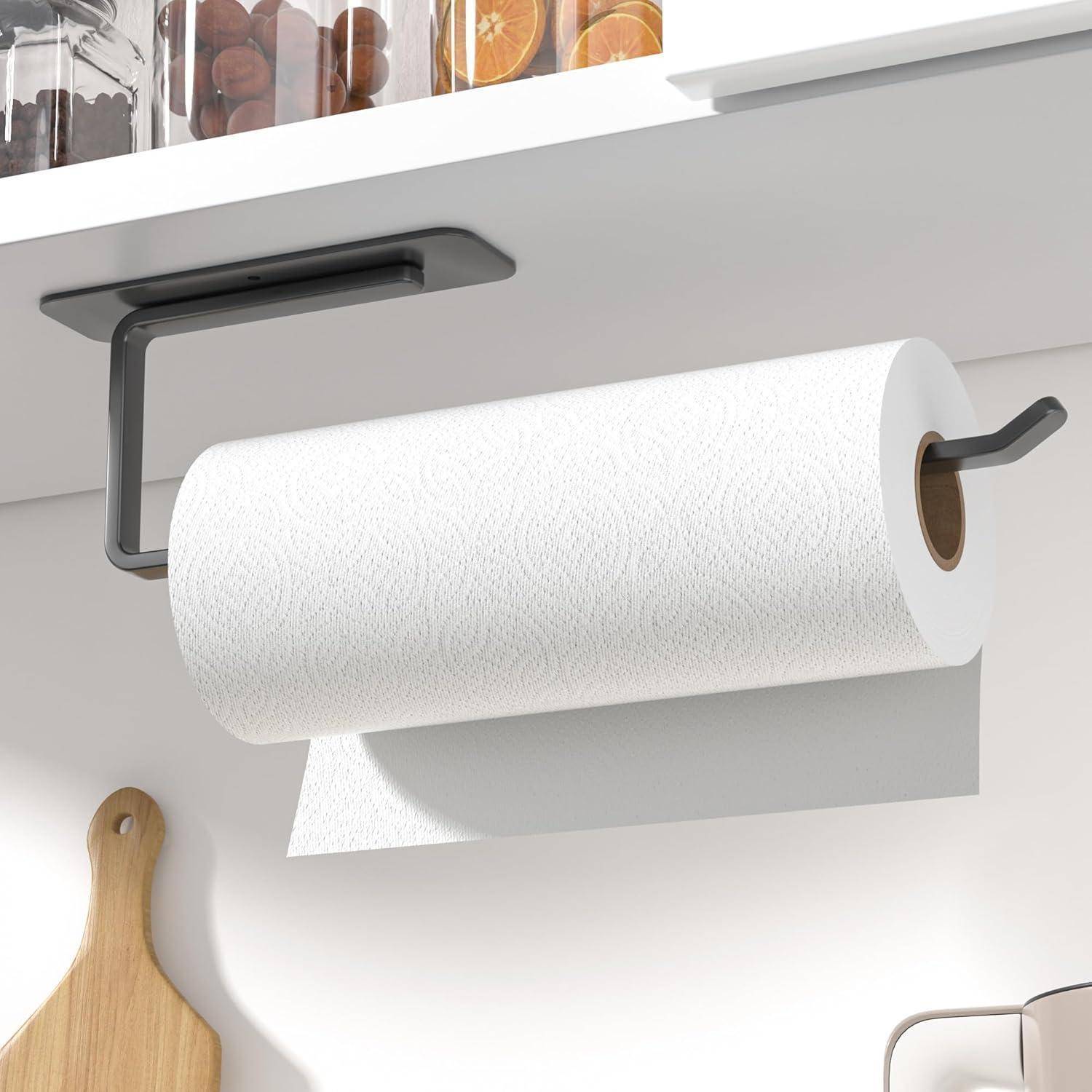 Eine Küche mit einer Rolle weißer Papiertücher auf einem an der Wand befestigten Halter. Ein hölzernes Schneidebrett hängt in der Nähe, und Regale enthalten Behälter.