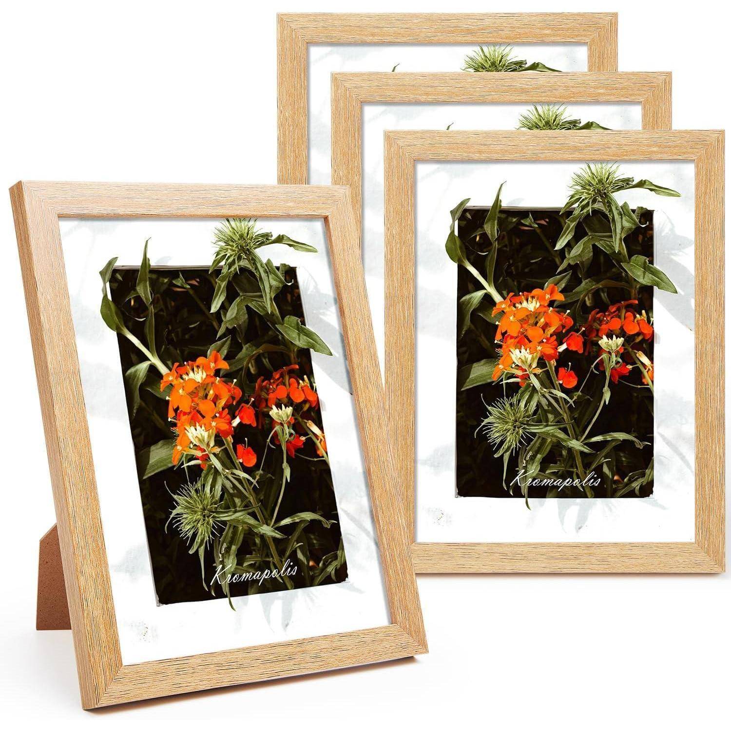 Drei Holzbilderrahmen, die einen botanischen Druck mit orangefarbenen und grünen Blüten mit dem Etikett „Kampalaia