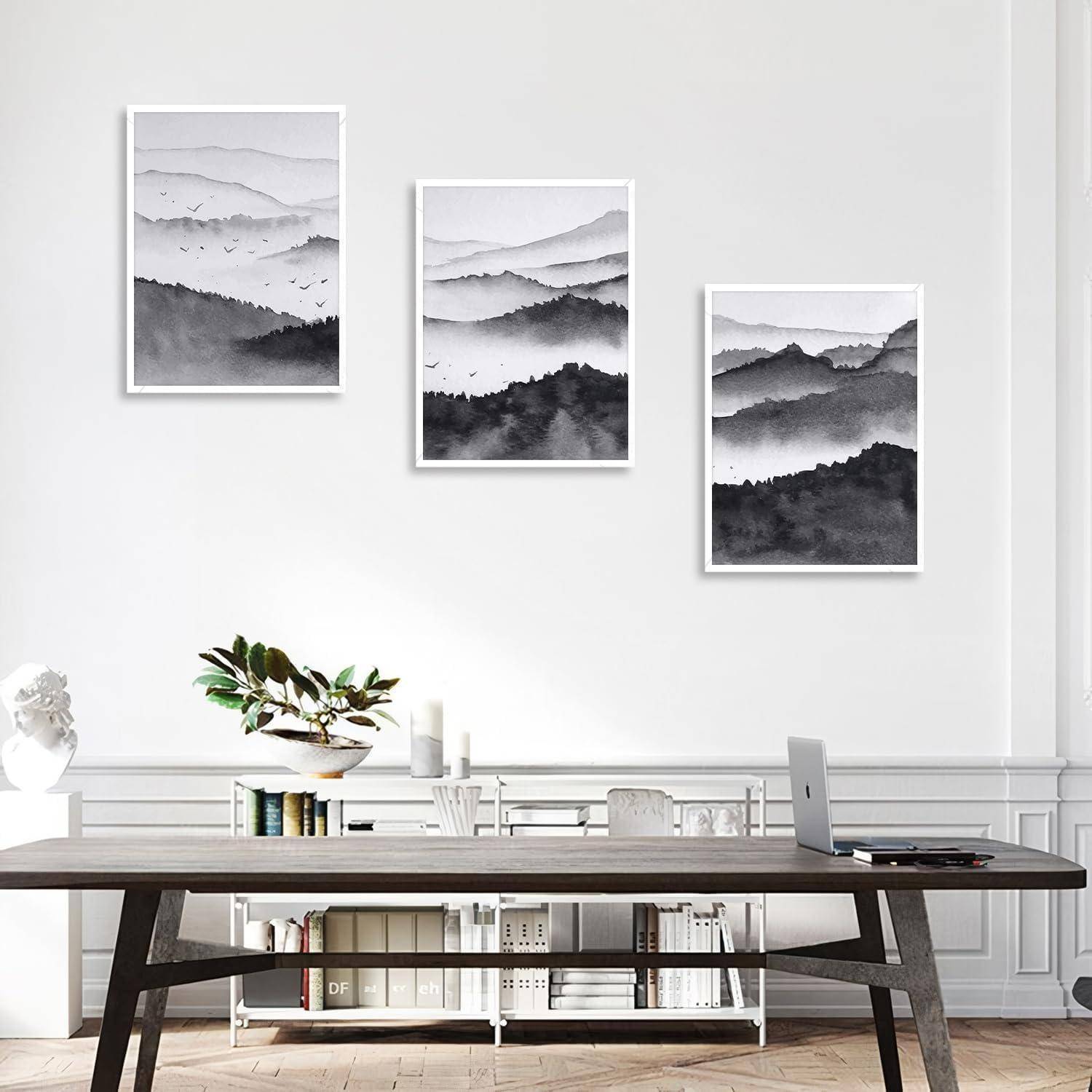 Ein modernes Zimmer mit einem Holztisch, Bücherregalen und drei gerahmten schwarzweißen Landschaftsfotografien an der Wand.