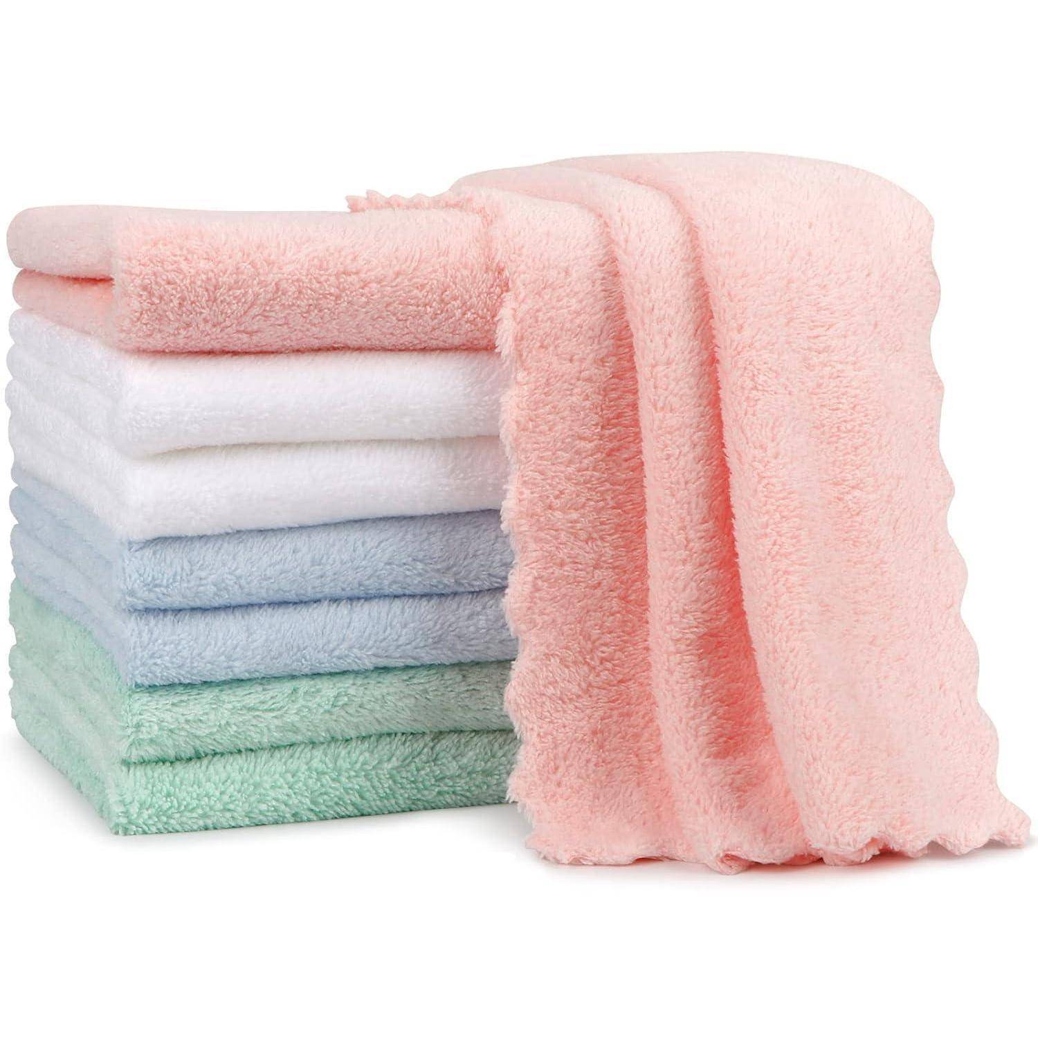 Ein Stapel von vier Handtüchern in Pastellfarben: Rosa, Weiß, Blau und Grün, mit einem rosafarbenen Handtuch, das oben darüber drapiert ist.