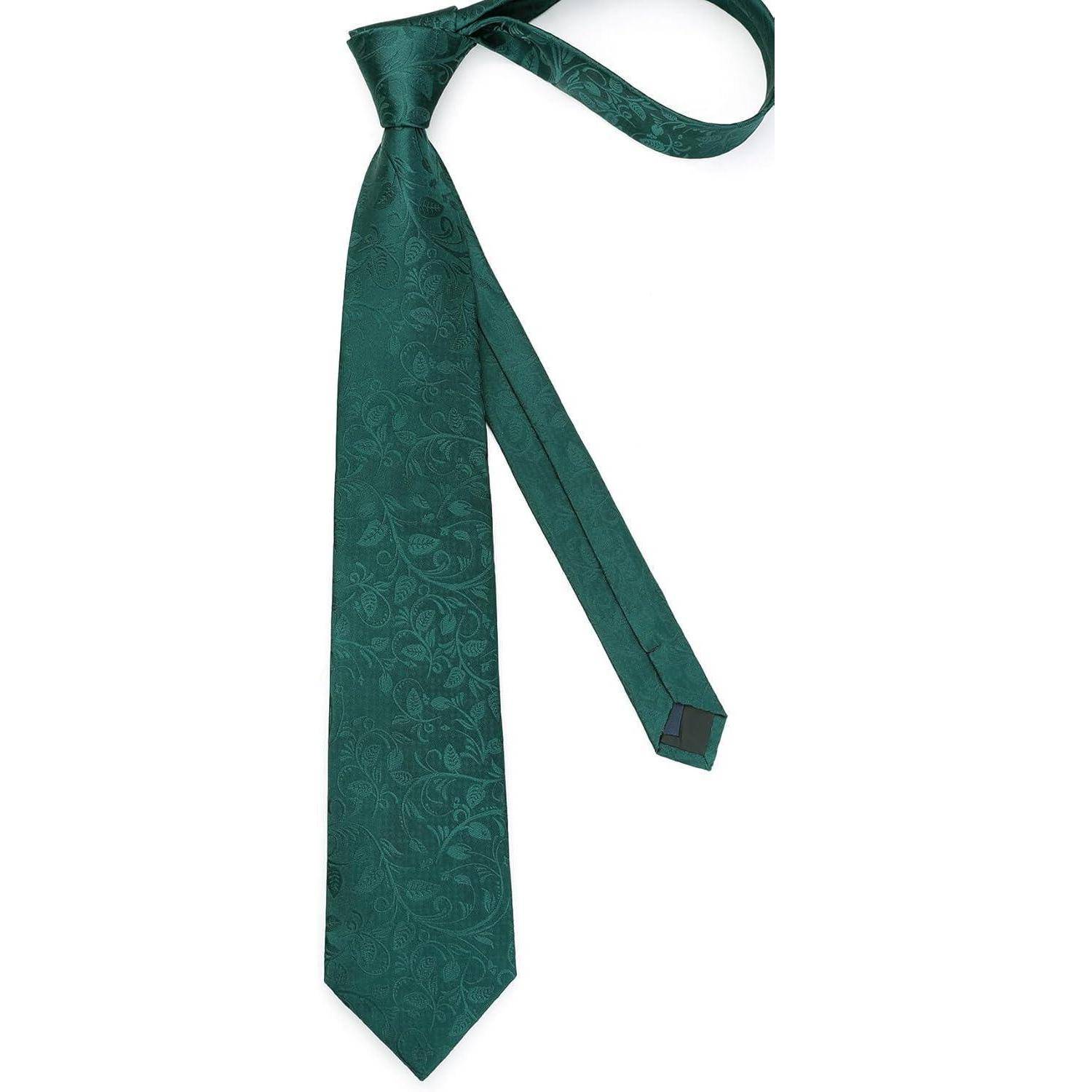 Eine grüne Seidenkrawatte mit einem subtilen Paisley-Muster, elegant drapiert mit einem Ende, das länger ist als das andere, was darauf hindeutet, dass sie gerade gebunden wird.