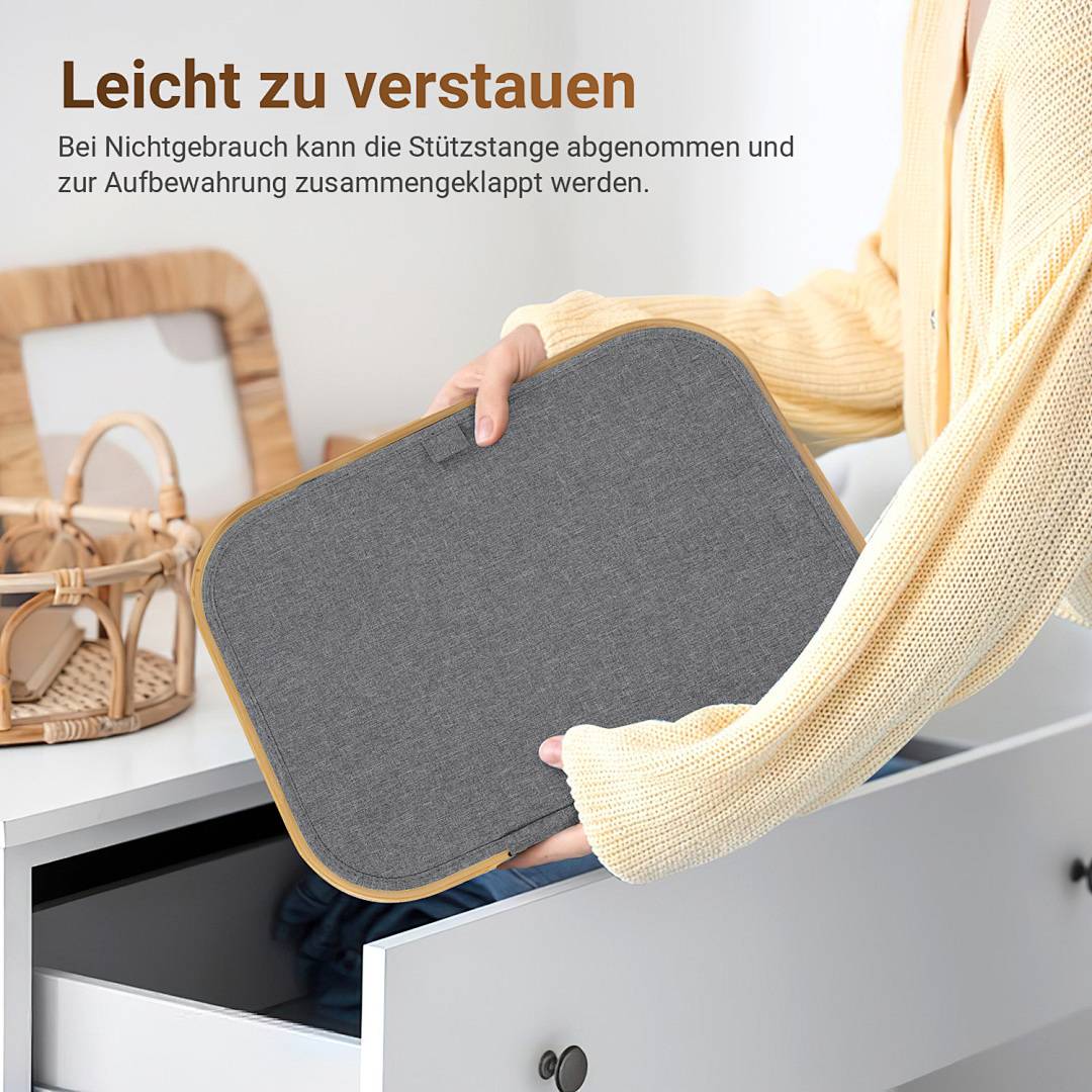 Eine Person in einem hellgefärbten Pullover legt einen gefalteten Gegenstand in eine Schublade. Eine geflochtene Tasche ist auf der linken Seite sichtbar. Text auf Deutsch ist vorhanden.