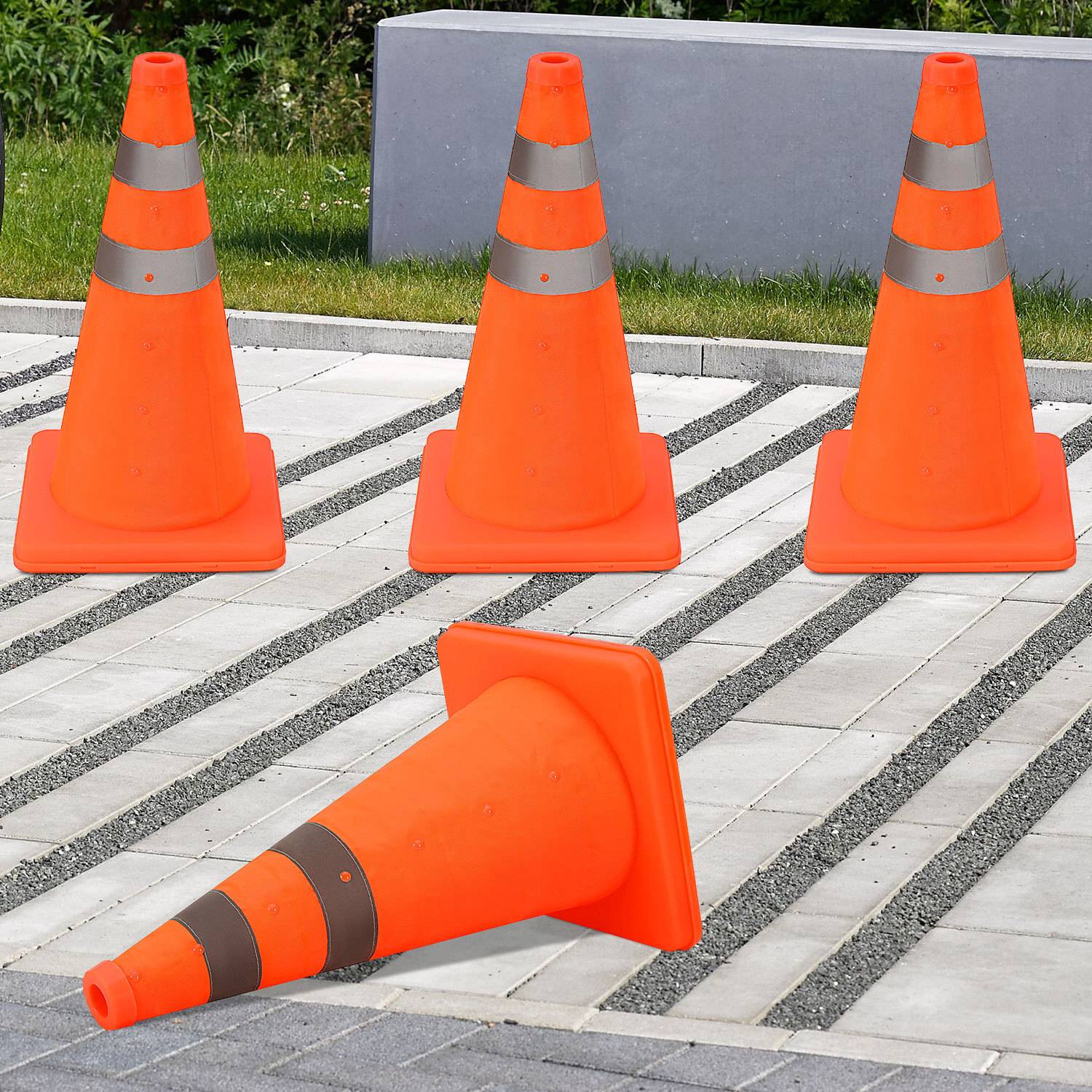 Mehrere orangefarbene Verkehrskegel auf einer gepflasterten Oberfläche, einer liegt umgekippt.