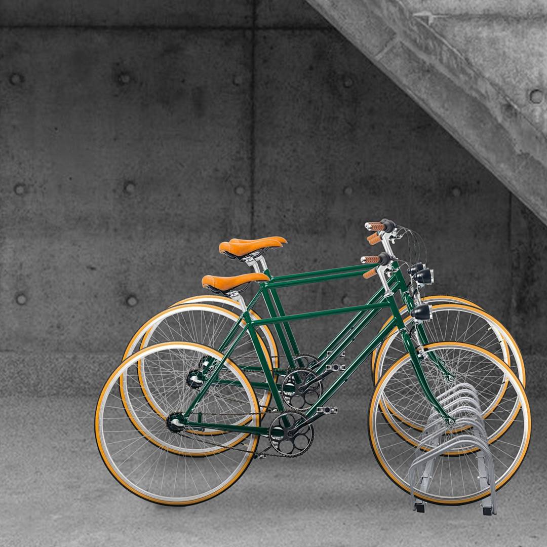 Ein grünes Fahrrad mit orangefarbenen Akzenten steht auf einer grauen Betonoberfläche und lehnt an einer Betonkonstruktion mit industriellem Design.