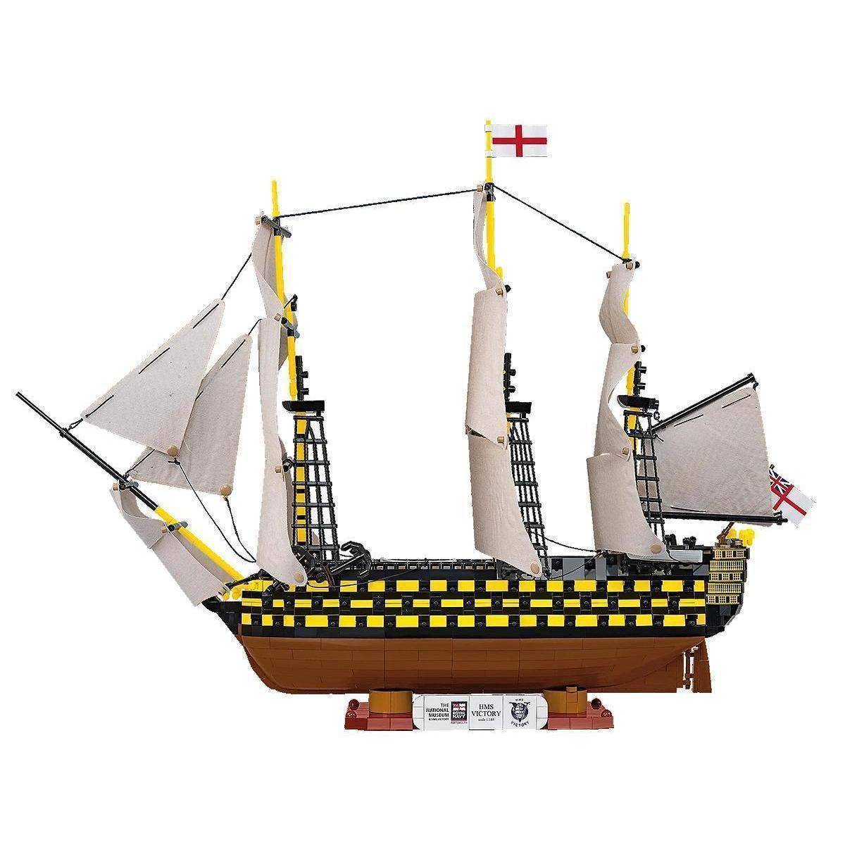 Ein komplexes Lego-Modell eines historischen Segelschiffs mit hohen Masten, Segeln und der Flagge des Heiligen Georg, ausgestellt auf einem Ständer.