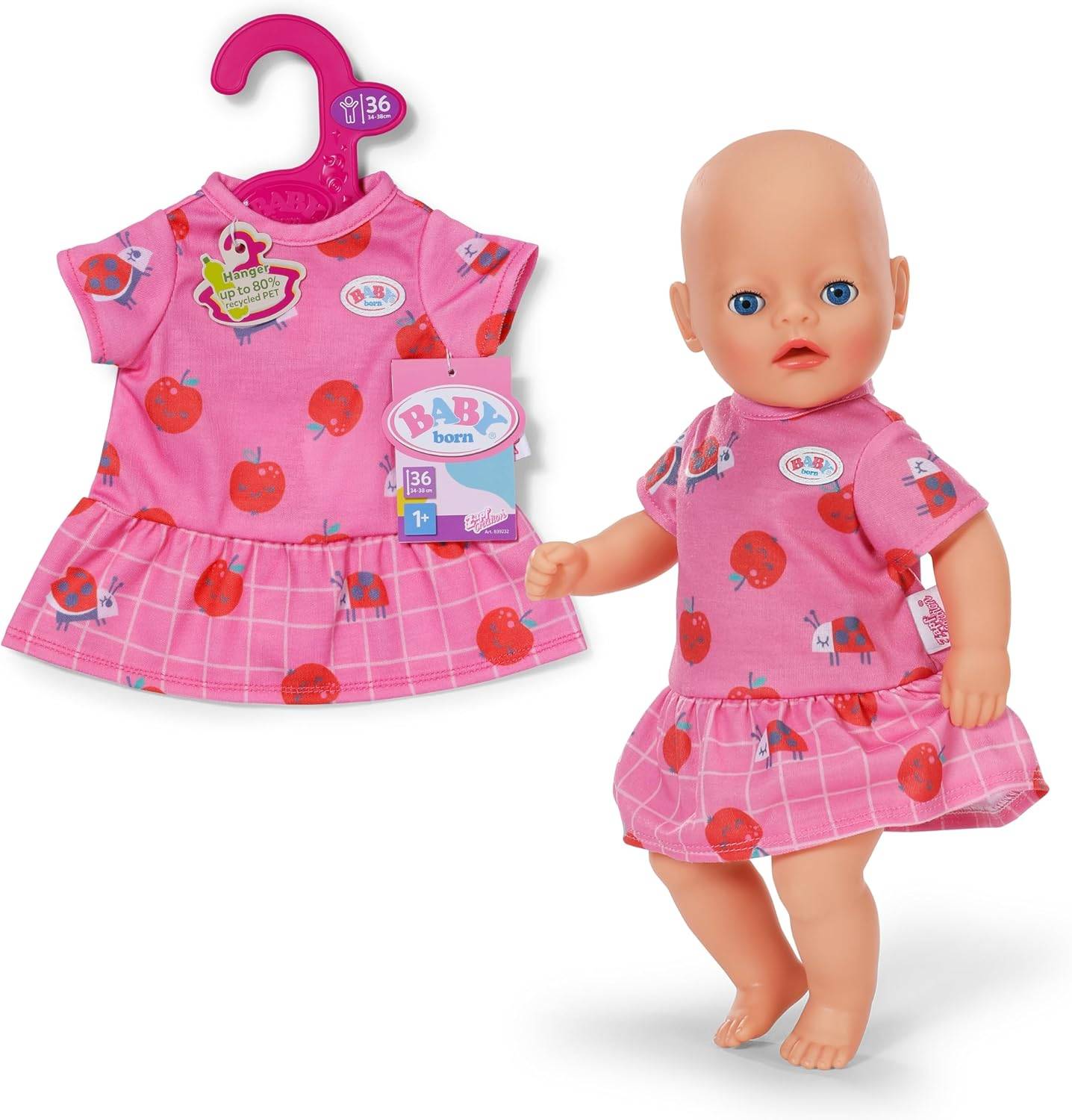 Eine realistische Babypuppe in einem rosa Kleid mit Apfelmuster, die neben einem passenden Outfit steht, das auf einem rosa Kleiderbügel hängt.
