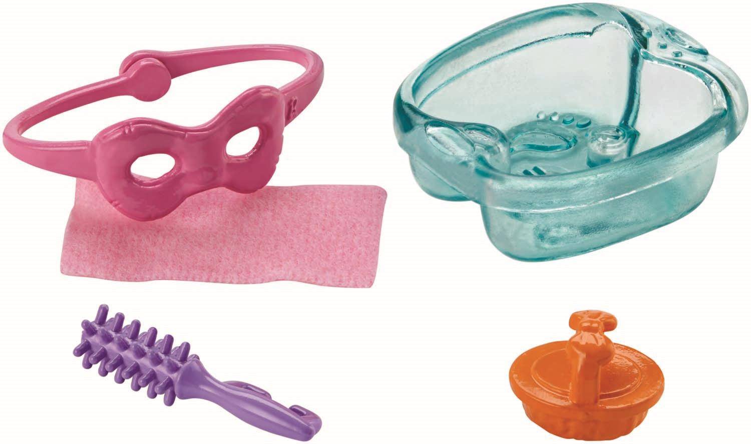 Eine Sammlung von rosa, türkisfarbenen und orangefarbenen Spielküchen-Artikeln auf weißem Hintergrund, einschließlich einer Rührschüssel, einem Sieb und einem Nudelholz.