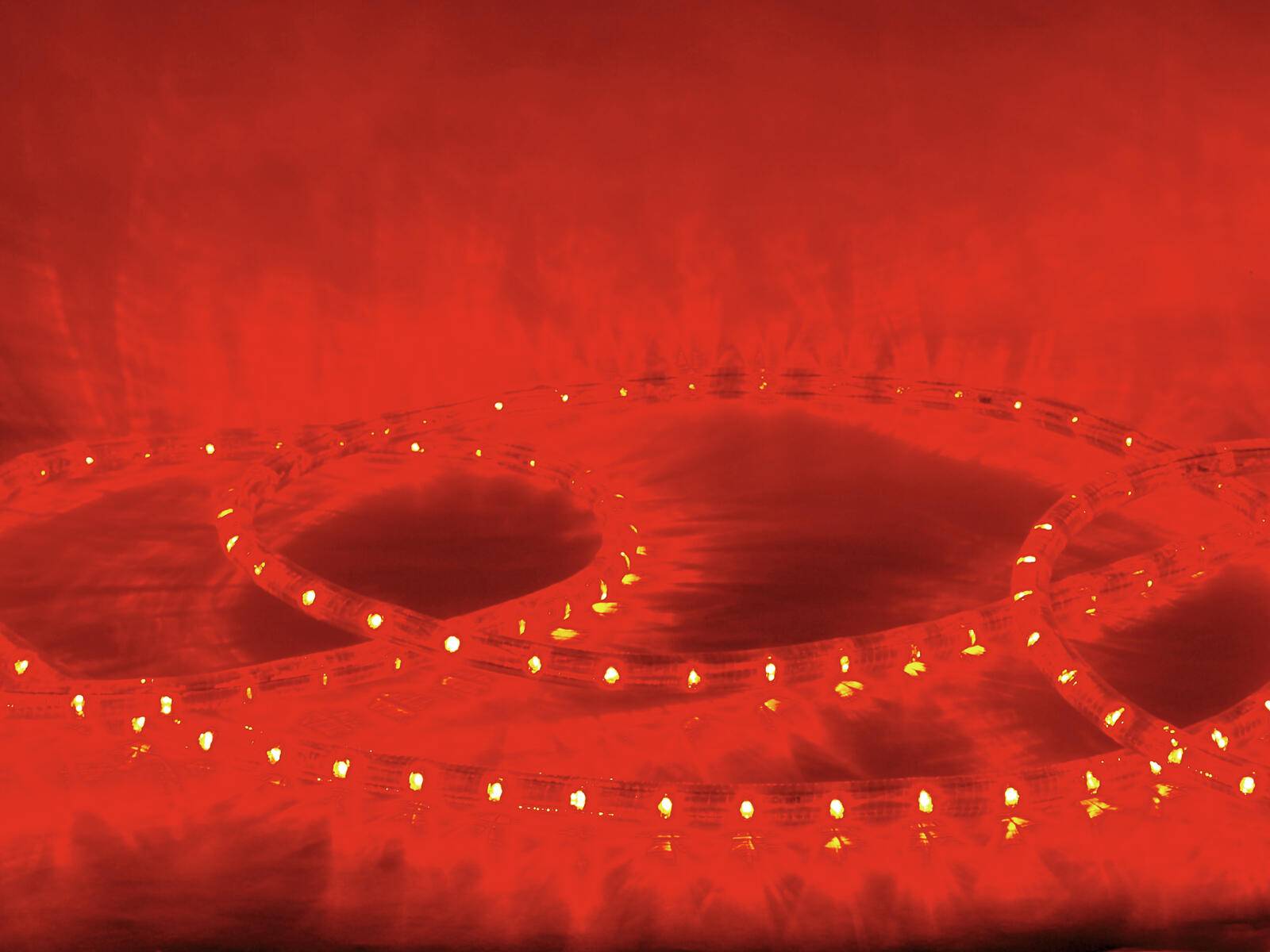 Ein rotes Lichtband bildet konzentrische Kreise auf dunklem Hintergrund und erzeugt einen leuchtenden, umgebungsreichen Effekt.