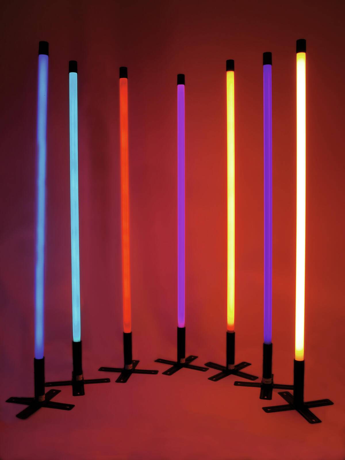 Sechs farbenfrohe Neonlichter in Blau, Rot und Orange, die vertikal vor einem dunklen Hintergrund stehen.