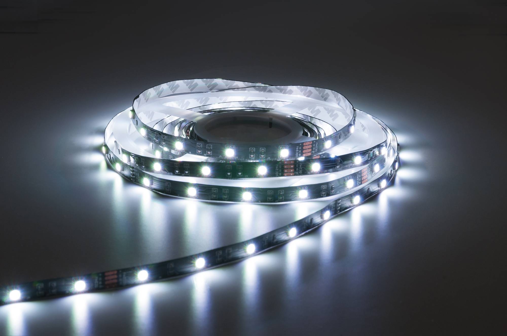 Ein aufgerolltes LED-Streifenlicht gibt ein helles, weißes Licht ab und beleuchtet seine unmittelbare Umgebung in einer schwach beleuchteten Umgebung.