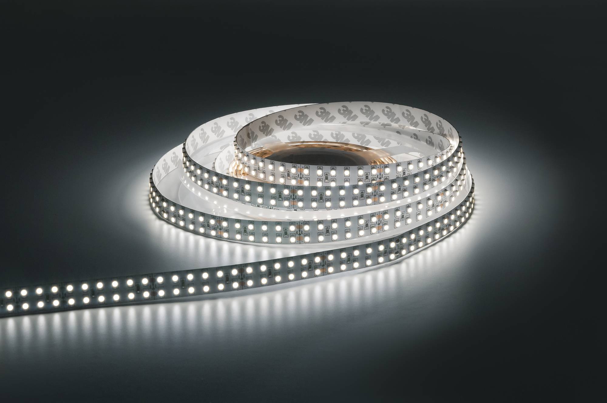 Eine Rolle weißer LED-Streifenlichter, die einen hellen Glanz auf einer dunklen Oberfläche ausstrahlen und das detaillierte Muster der LEDs hervorheben.