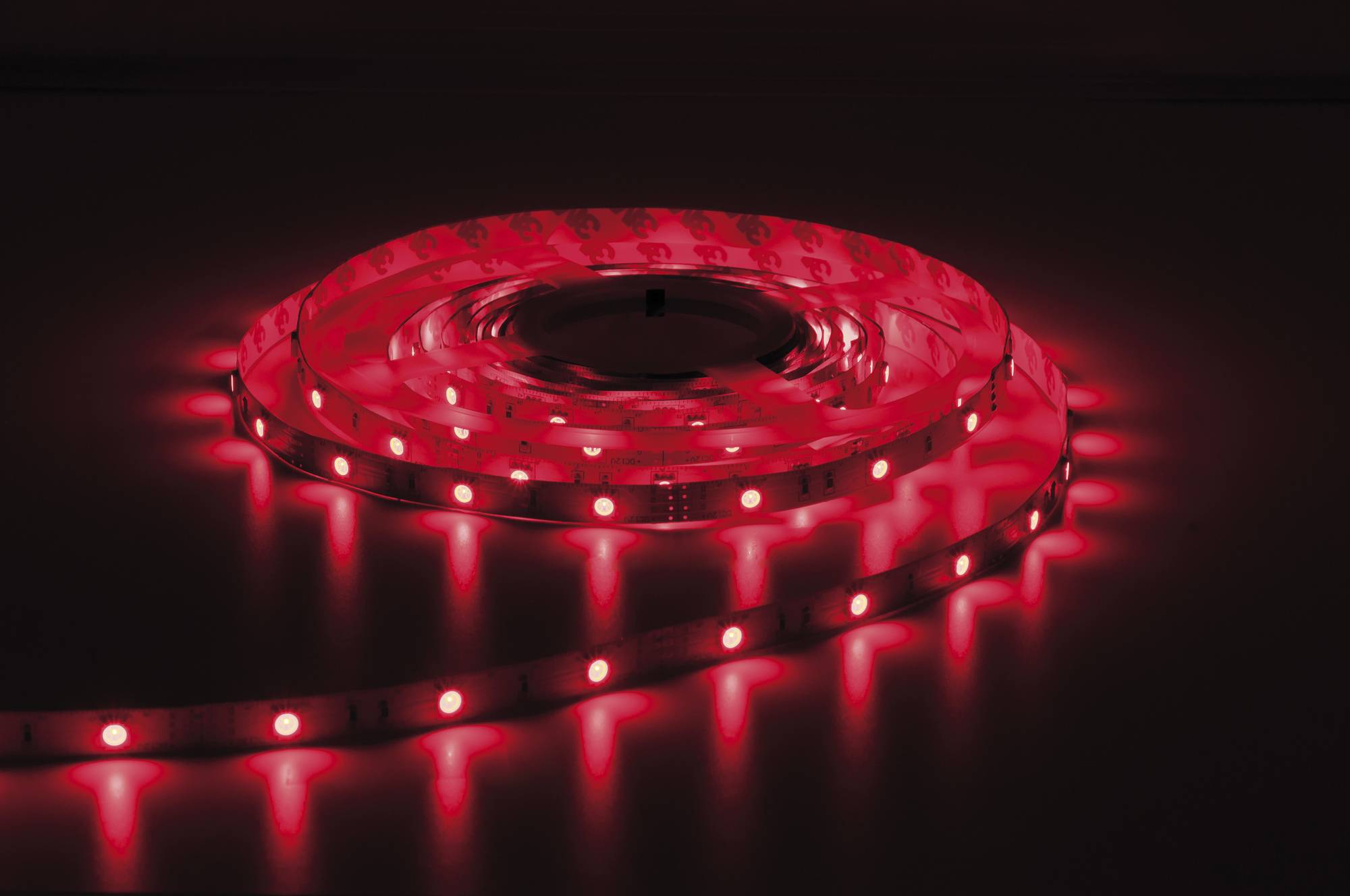 Ein leuchtender roter LED-Streifenlichter, das in einem Spiralmuster auf einer dunklen Oberfläche angeordnet ist, das ein lebhaftes und stimmungsvolles rotes Licht ausstrahlt.