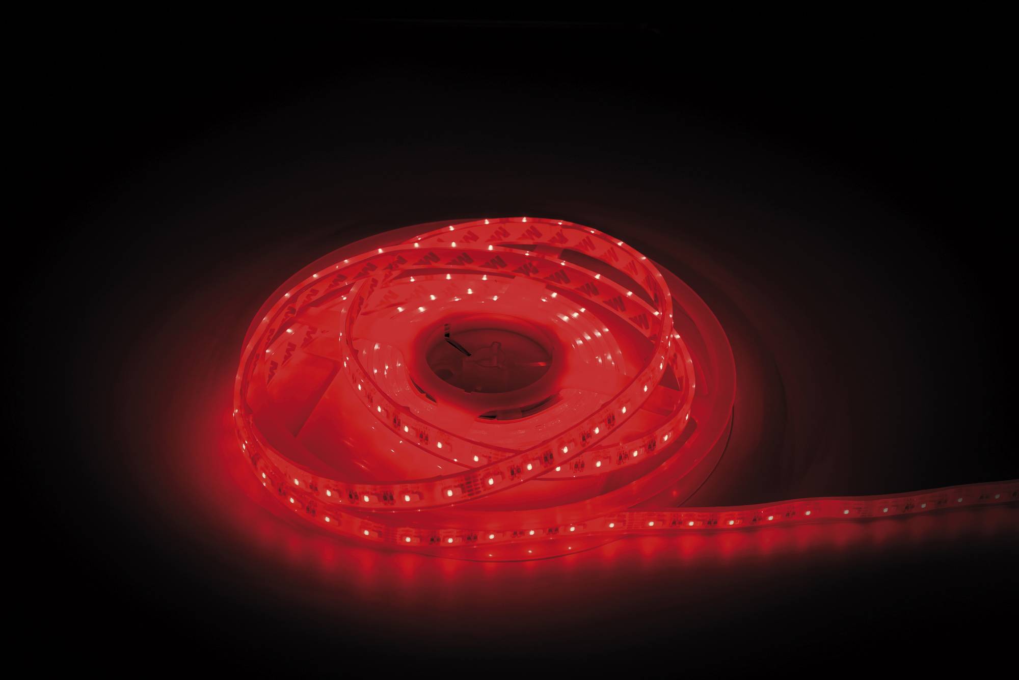 Ein glühendes rotes LED-Streifenlicht, das in einer dunklen Umgebung aufgewickelt ist und ein sanftes, warmes Licht ausstrahlt, das seine Flexibilität und Leuchtkraft unterstreicht.