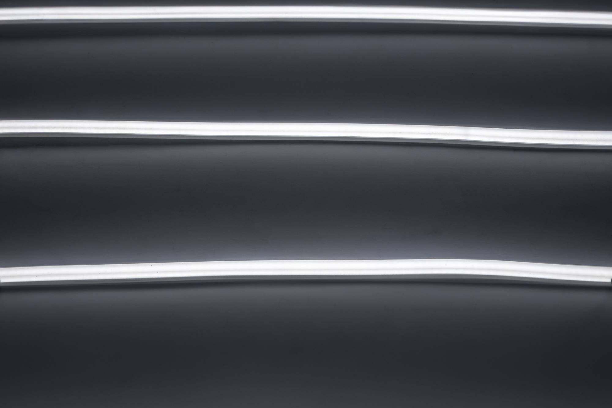 Drei parallele horizontale Neonlichter auf dunklem Hintergrund.